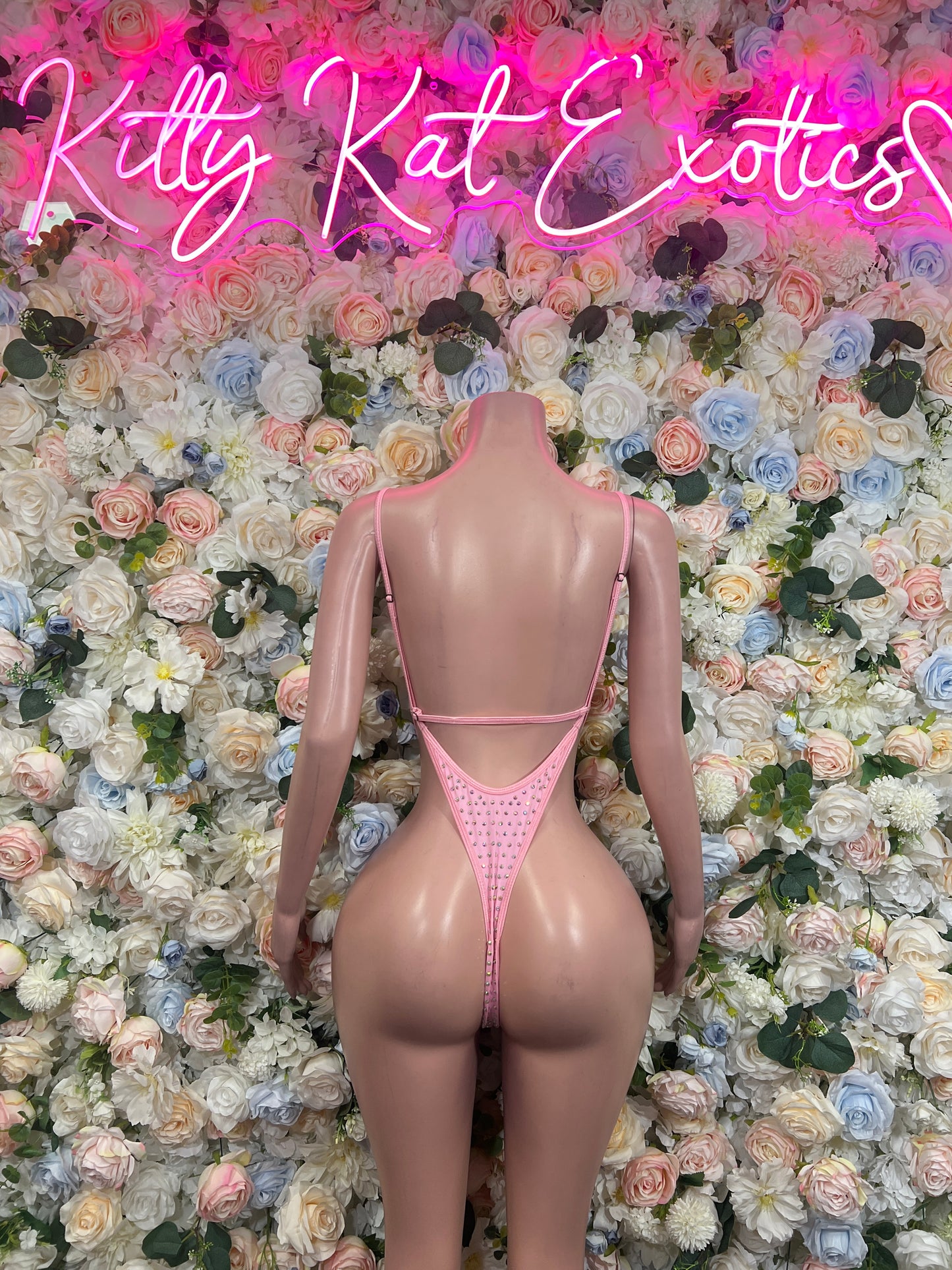 Pink rhinestone one-piece bodysuit with V-back straps and high-cut coverage