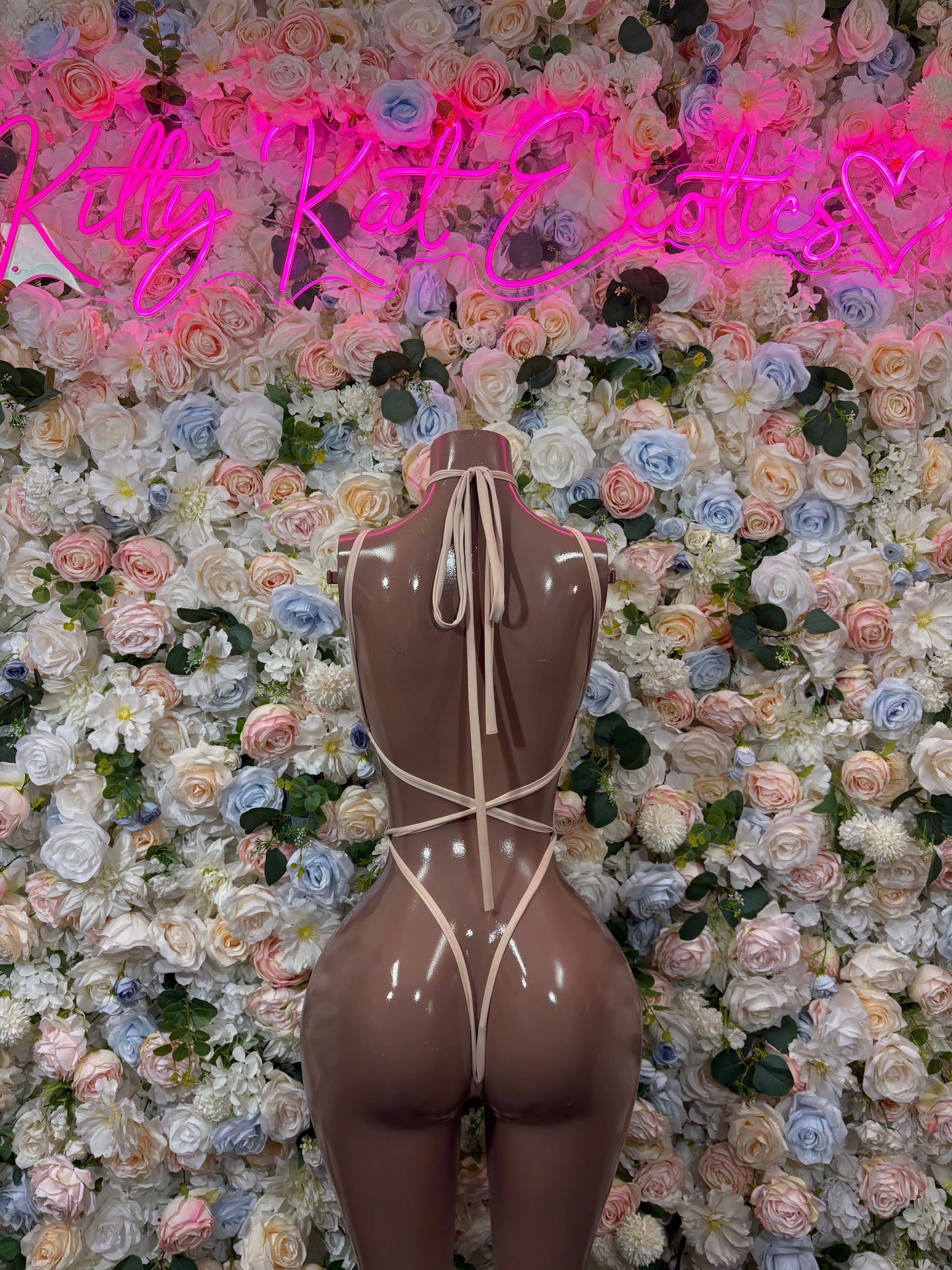 One-piece nude bodysuit with crisscross back straps, high-cut leg, back on mannequin