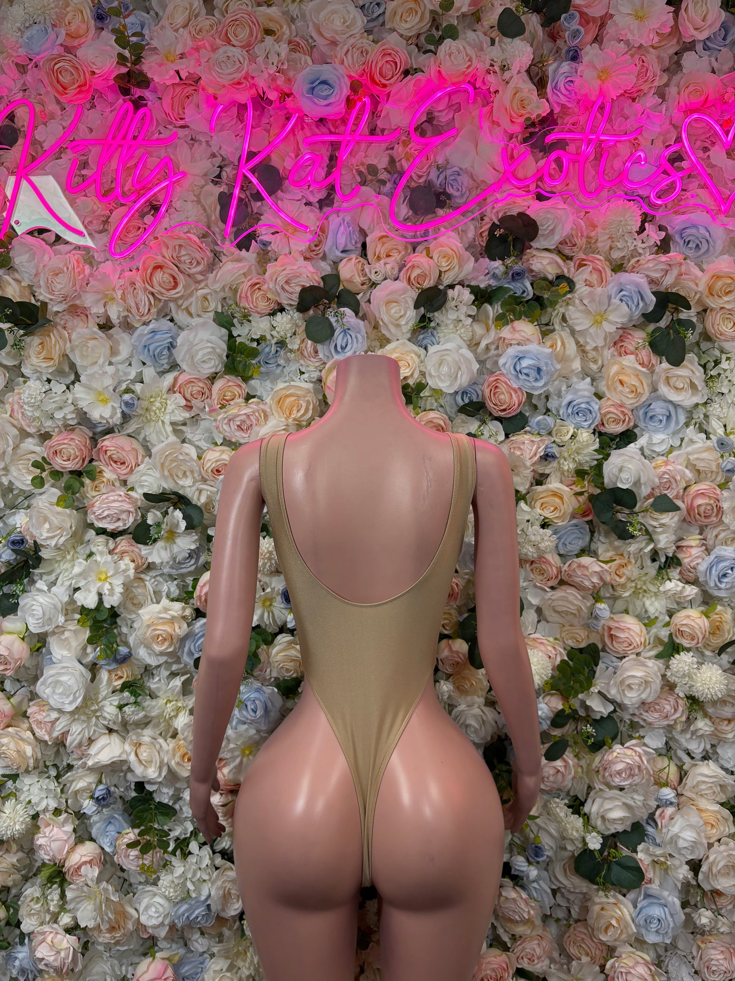 Tan one-piece bodysuit with low open back and ruched back seam