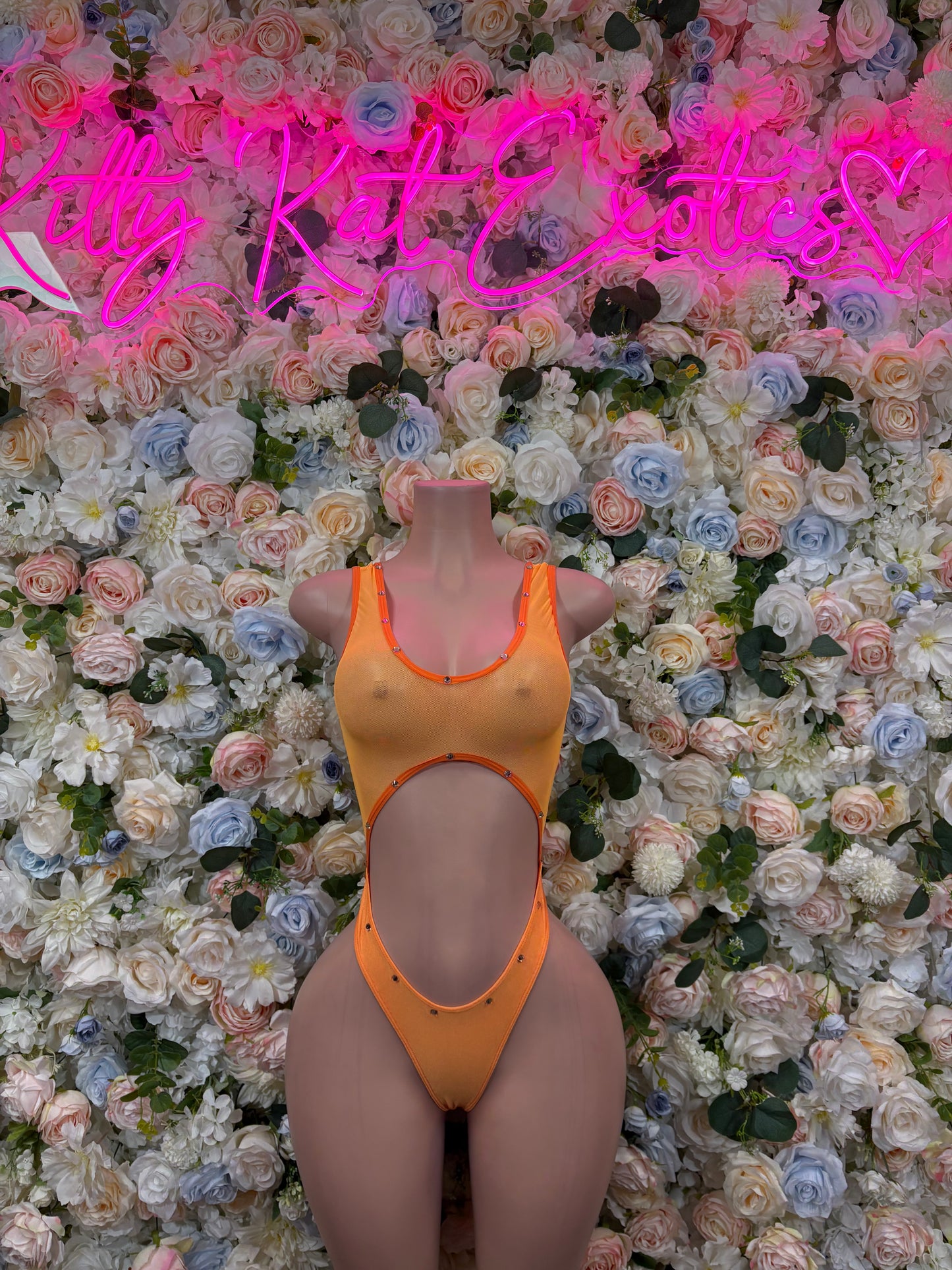 Orange one-piece bodysuit with thin straps and high-cut legs on mannequin