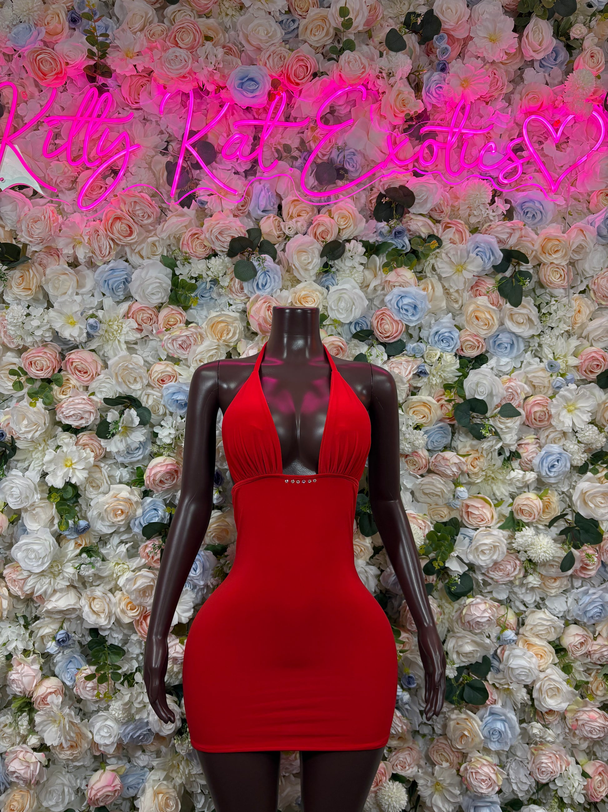 Red halter mini dress on mannequin, fitted sleeveless design with scoop neckline