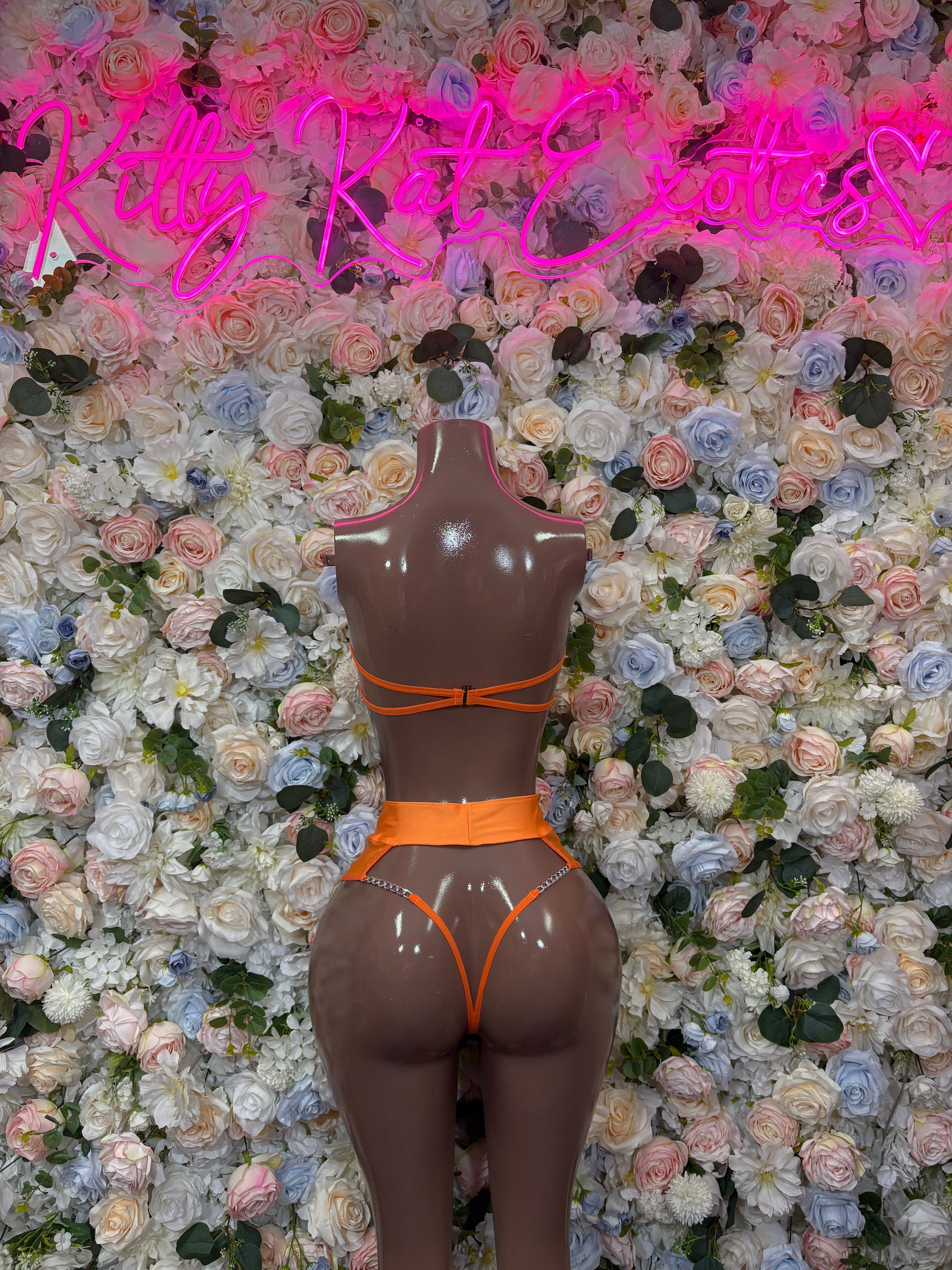 Orange two-piece bikini set on mannequin, triangle top and high-cut bottoms