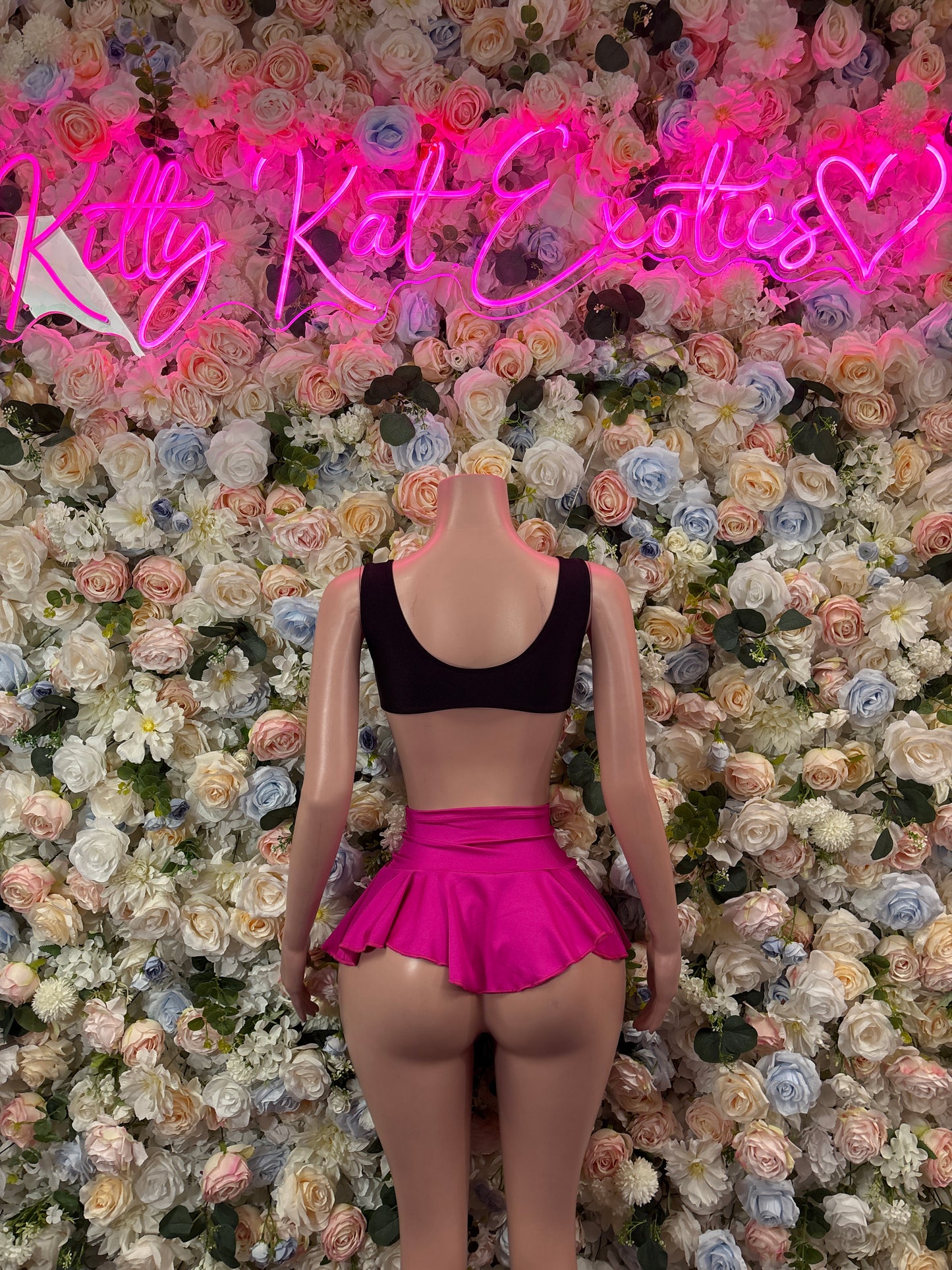Two-piece skirt set with black bikini top and hot pink ruffle mini skirt, tied back