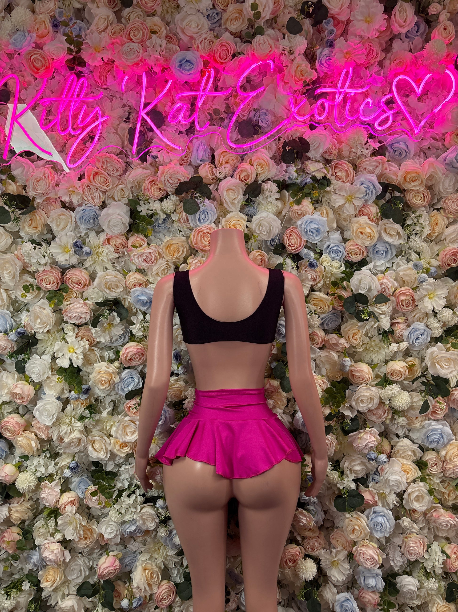 Two-piece skirt set with black bikini top and hot pink ruffle mini skirt, tied back
