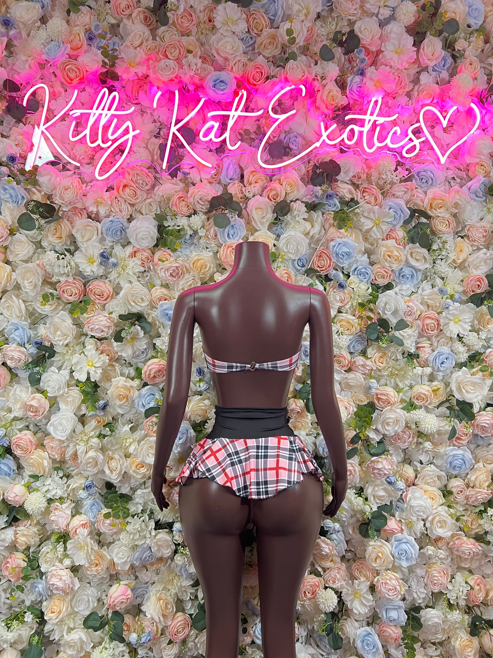 Pink plaid two-piece skirt set with plaid top and black waist belt on mannequin, back