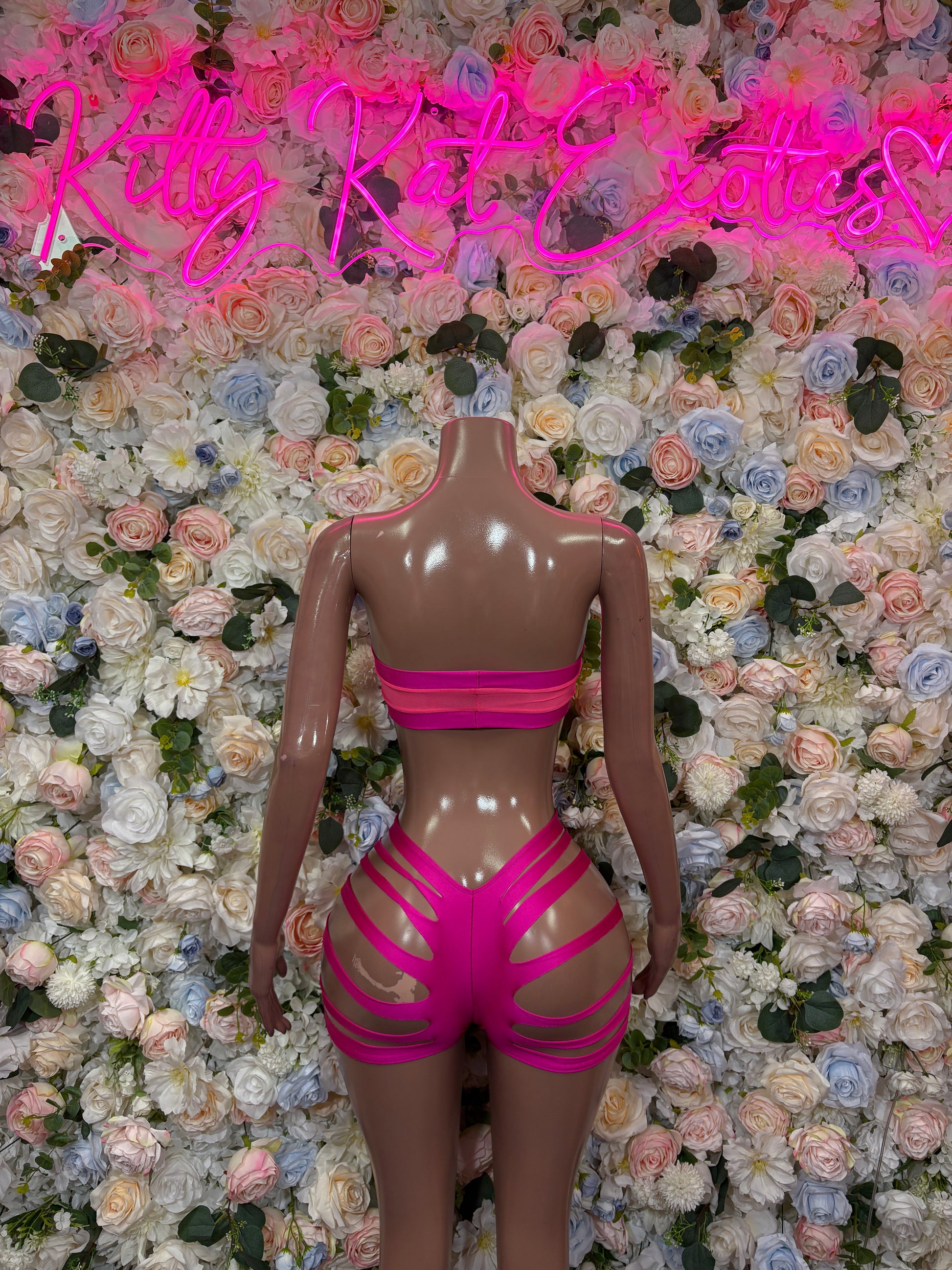Pink two-piece rave set: bandeau bikini top with high-waist cutout shorts on mannequin