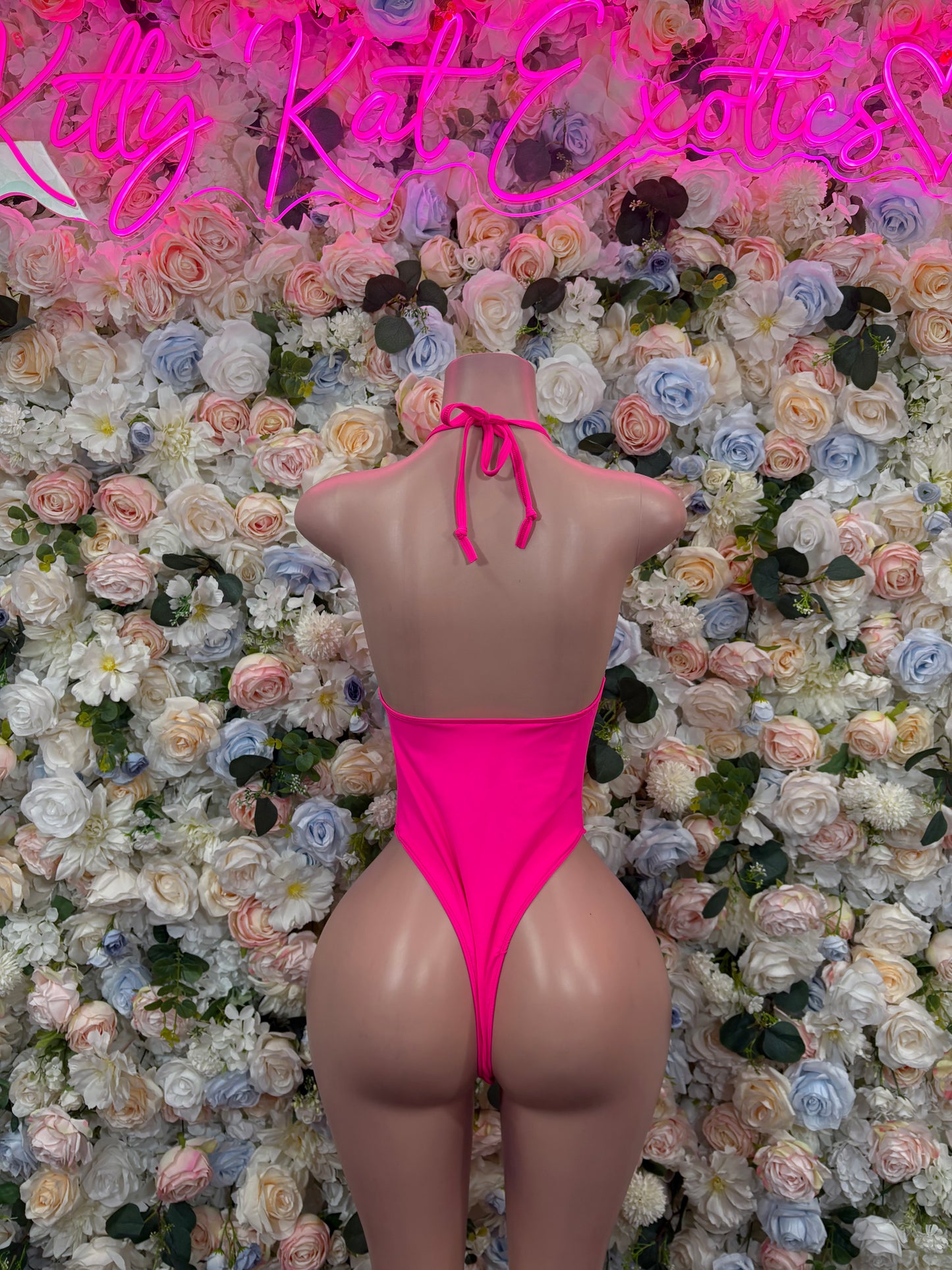 Hot pink sleeveless one-piece bodysuit with open back and bow-tie straps at neck