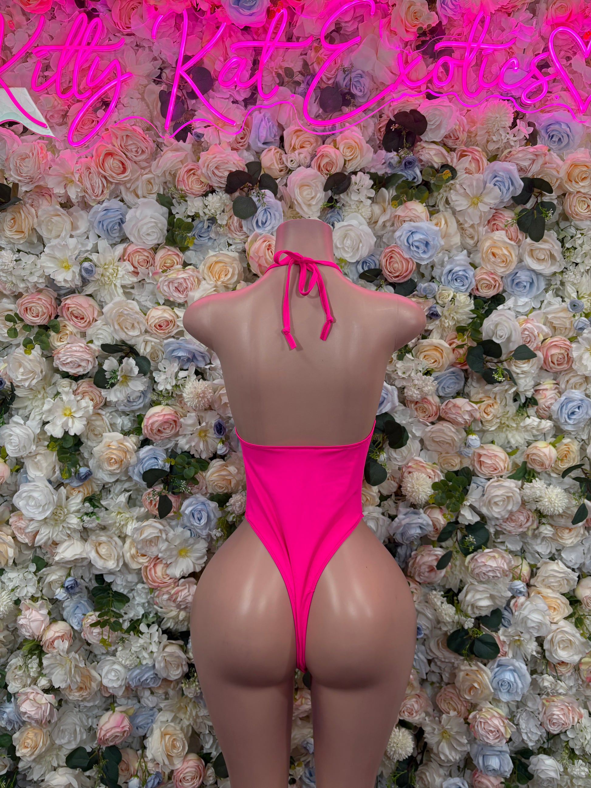 Hot pink sleeveless one-piece bodysuit with open back and bow-tie straps at neck