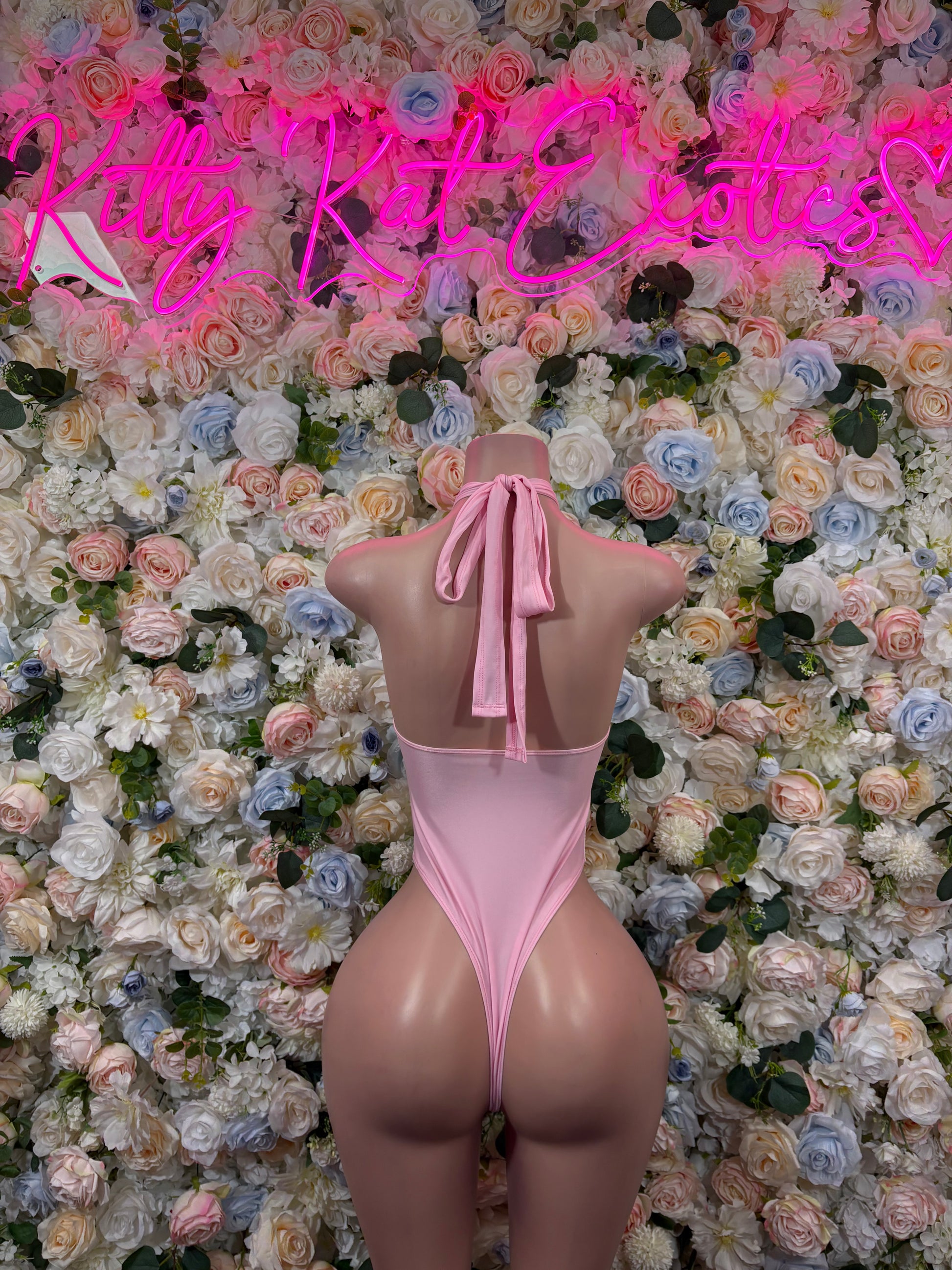 Pink velvet-style halter bodysuit back view with tied neck, open back, on mannequin