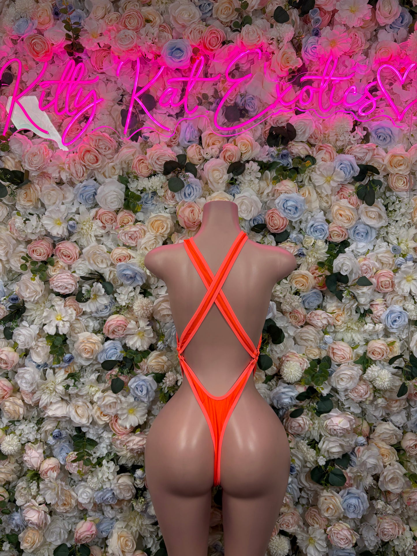 Orange open-back halter bodysuit with crisscross straps and thong-style bottom