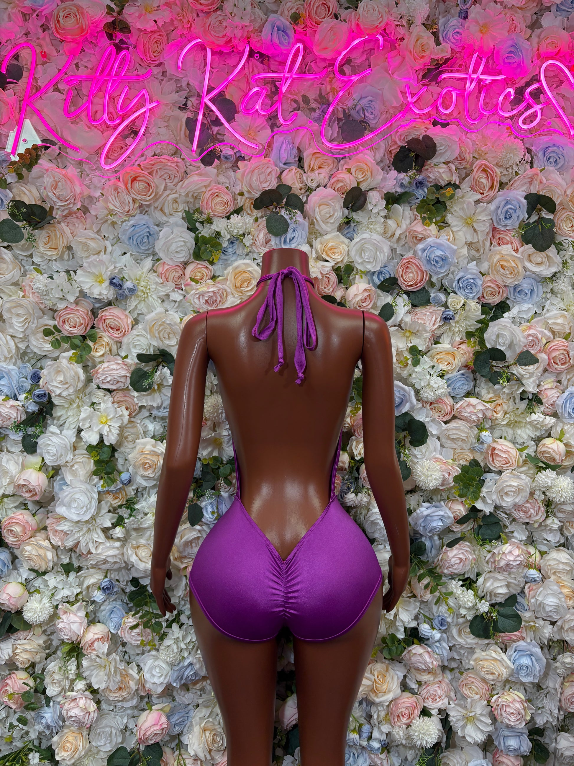 Purple open-back one-piece rave bodysuit with halter straps and tied back neckline