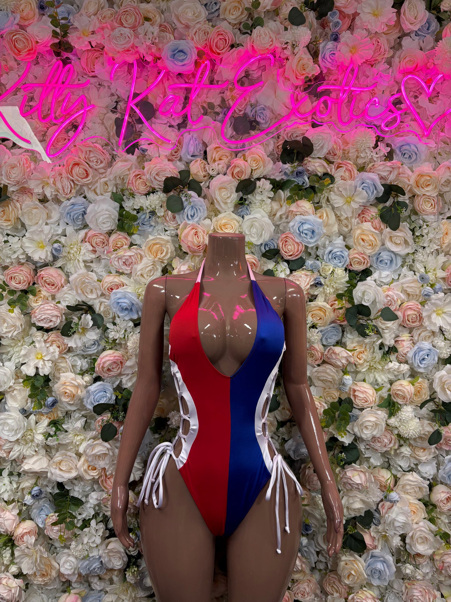 Tricolor Dominican flag bodysuit with blue front, red sides, and white trim; lace ties.
