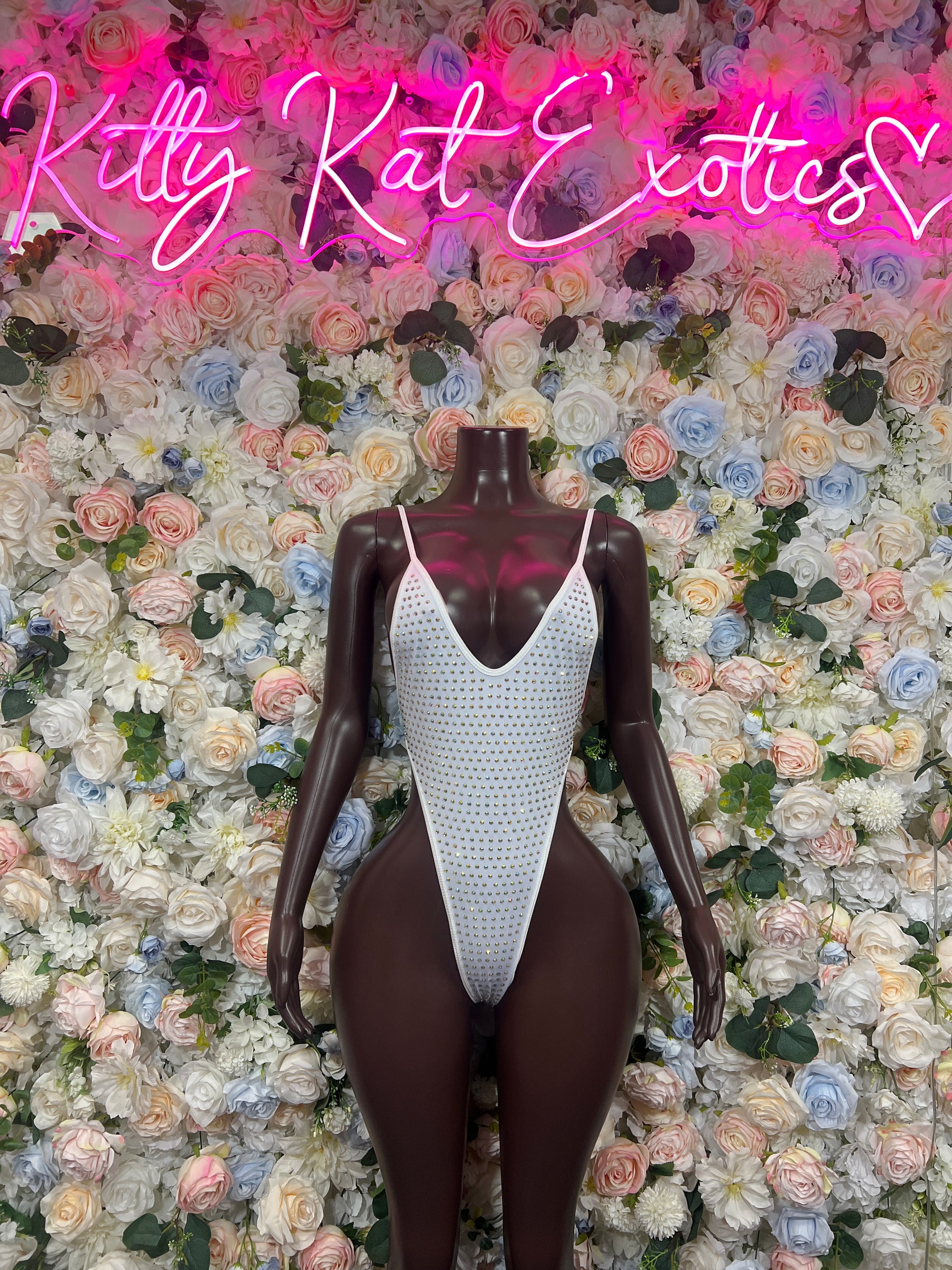 White rhinestone V-neck bodysuit on mannequin, high-cut one-piece with thin straps