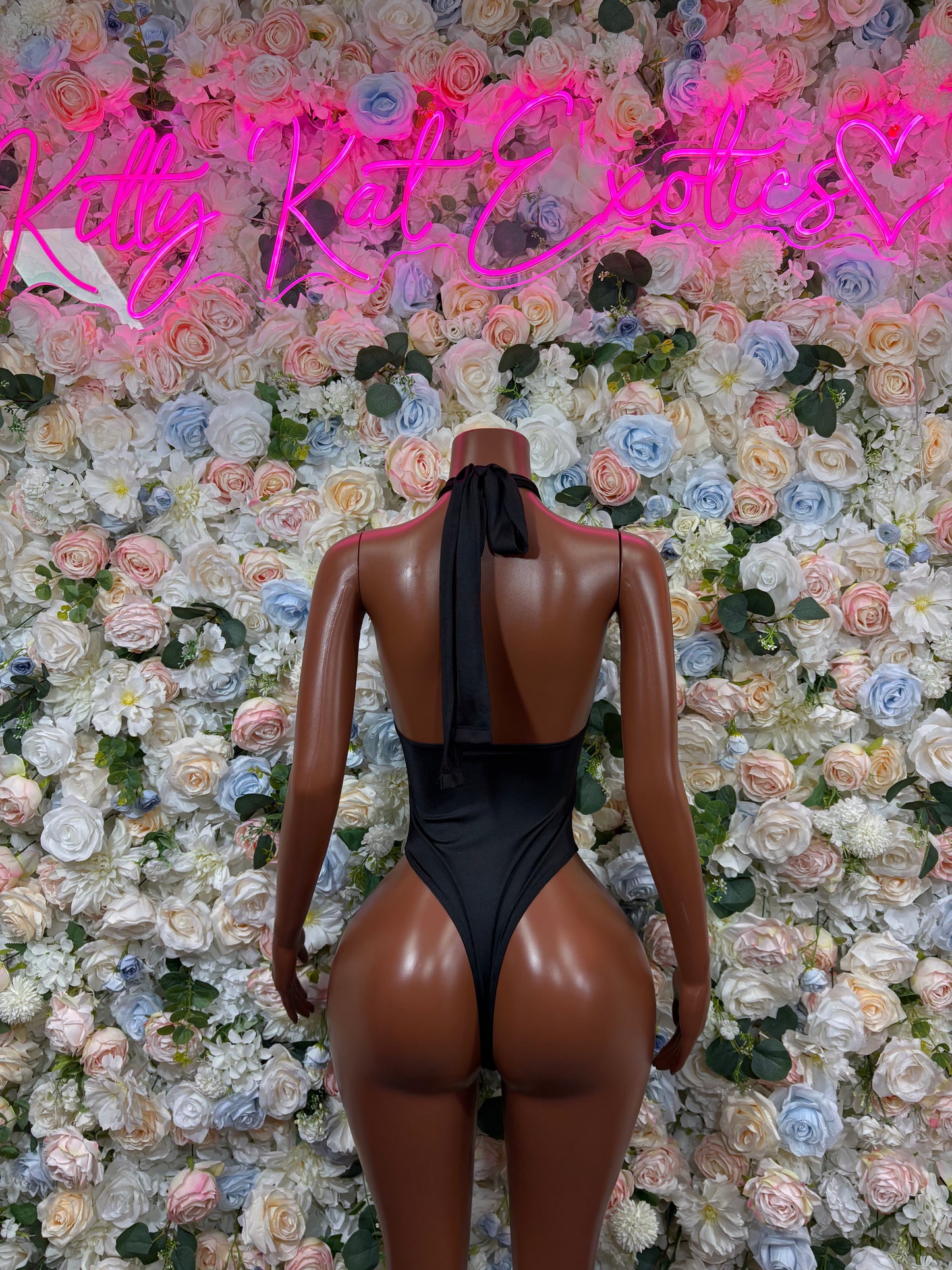 Black backless one-piece bodysuit with high-cut legs and studded straps