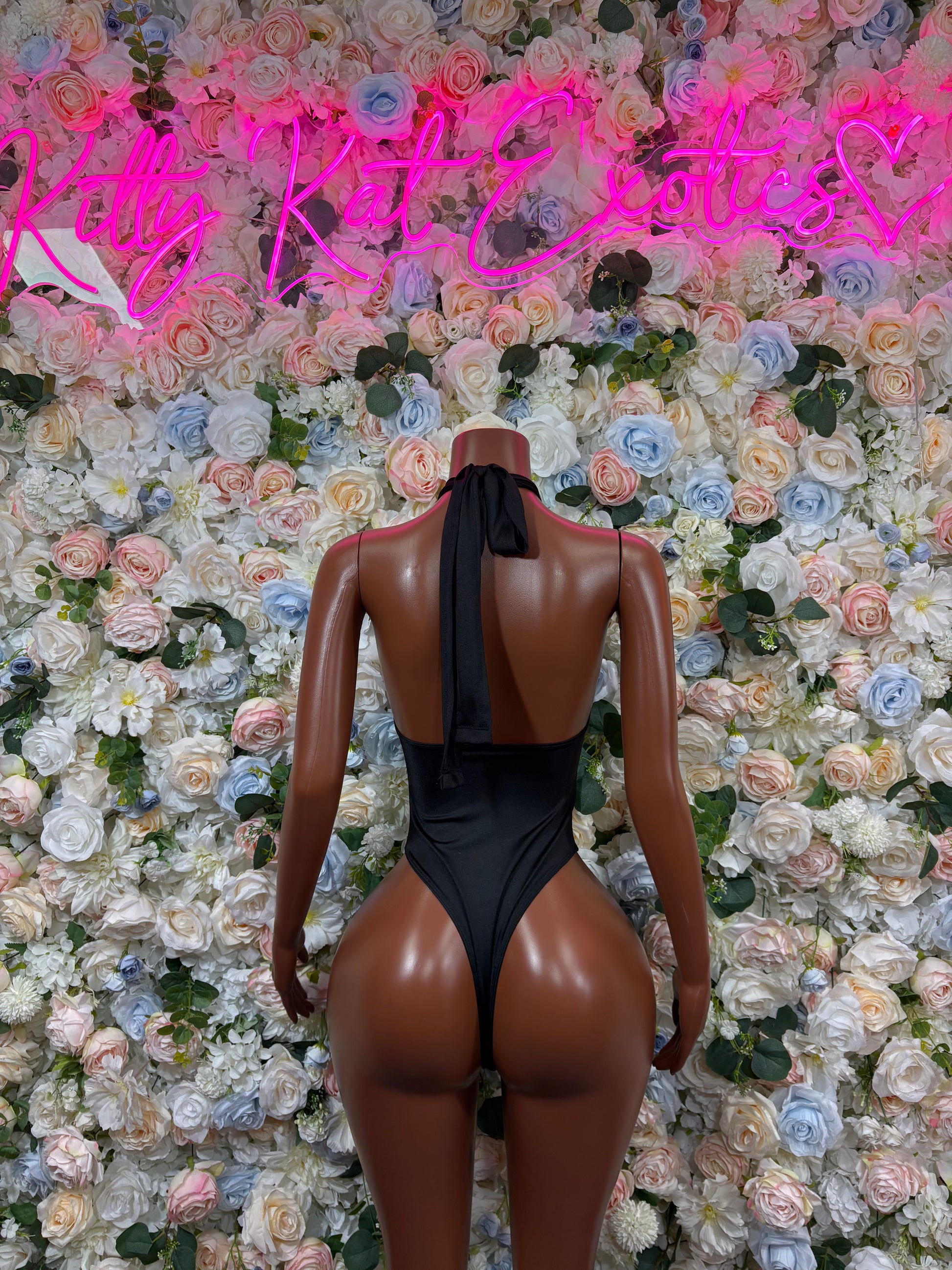 Black backless one-piece bodysuit with high-cut legs and studded straps