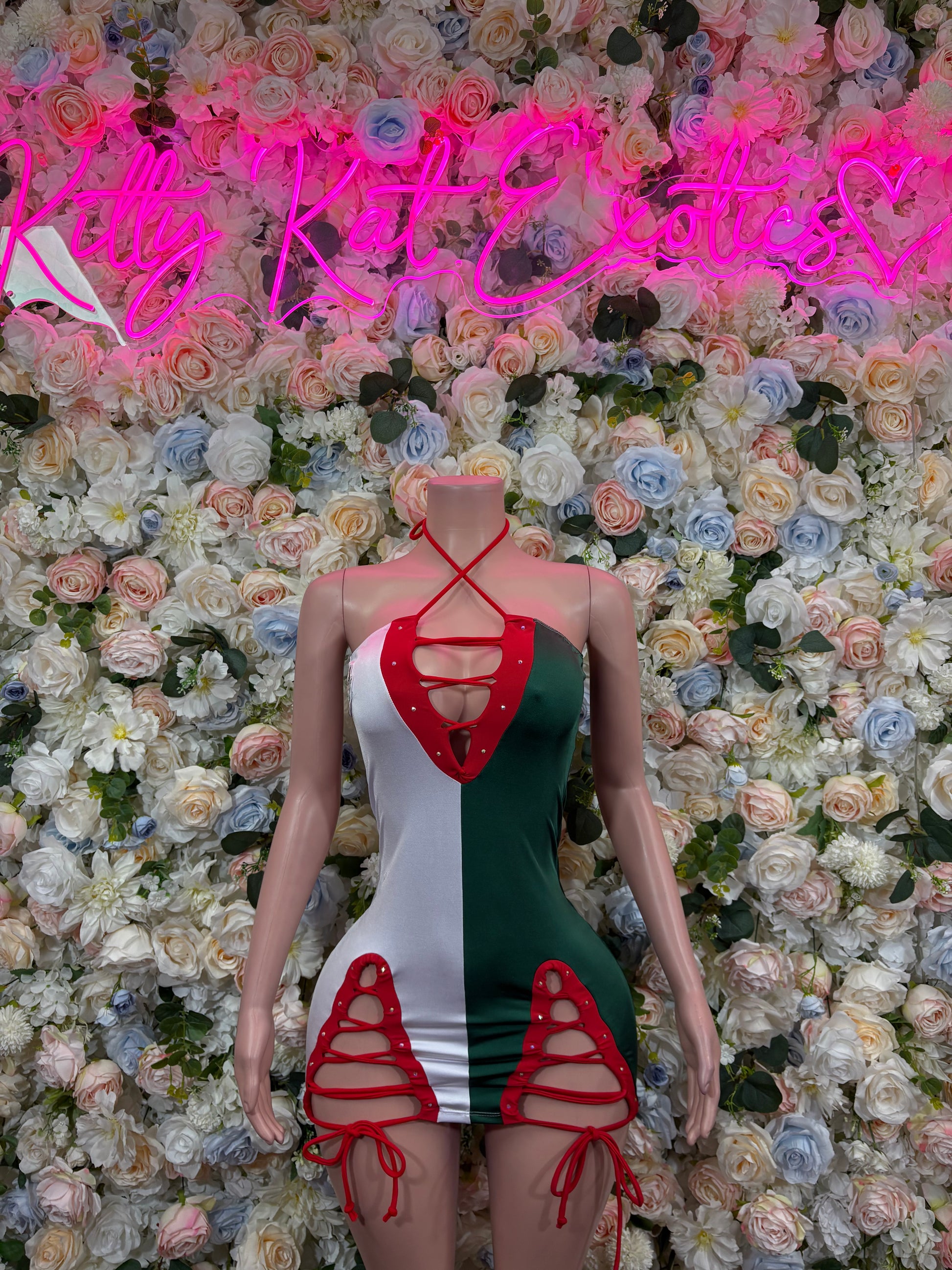 Mini dress in green, white, and red with cutout straps and tie-back.