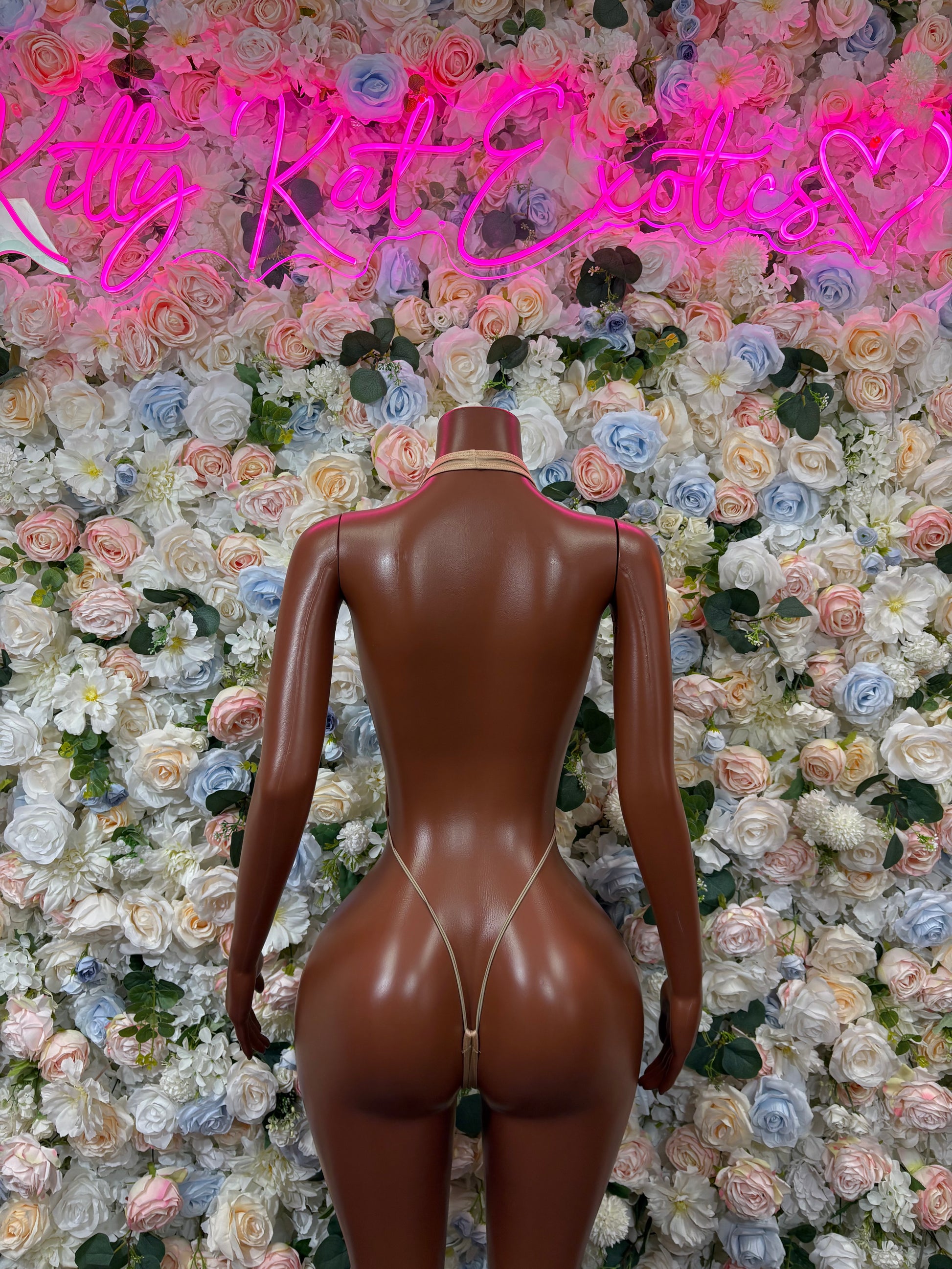 Tan slingshot bodysuit with low back and thong-style strap detail.
