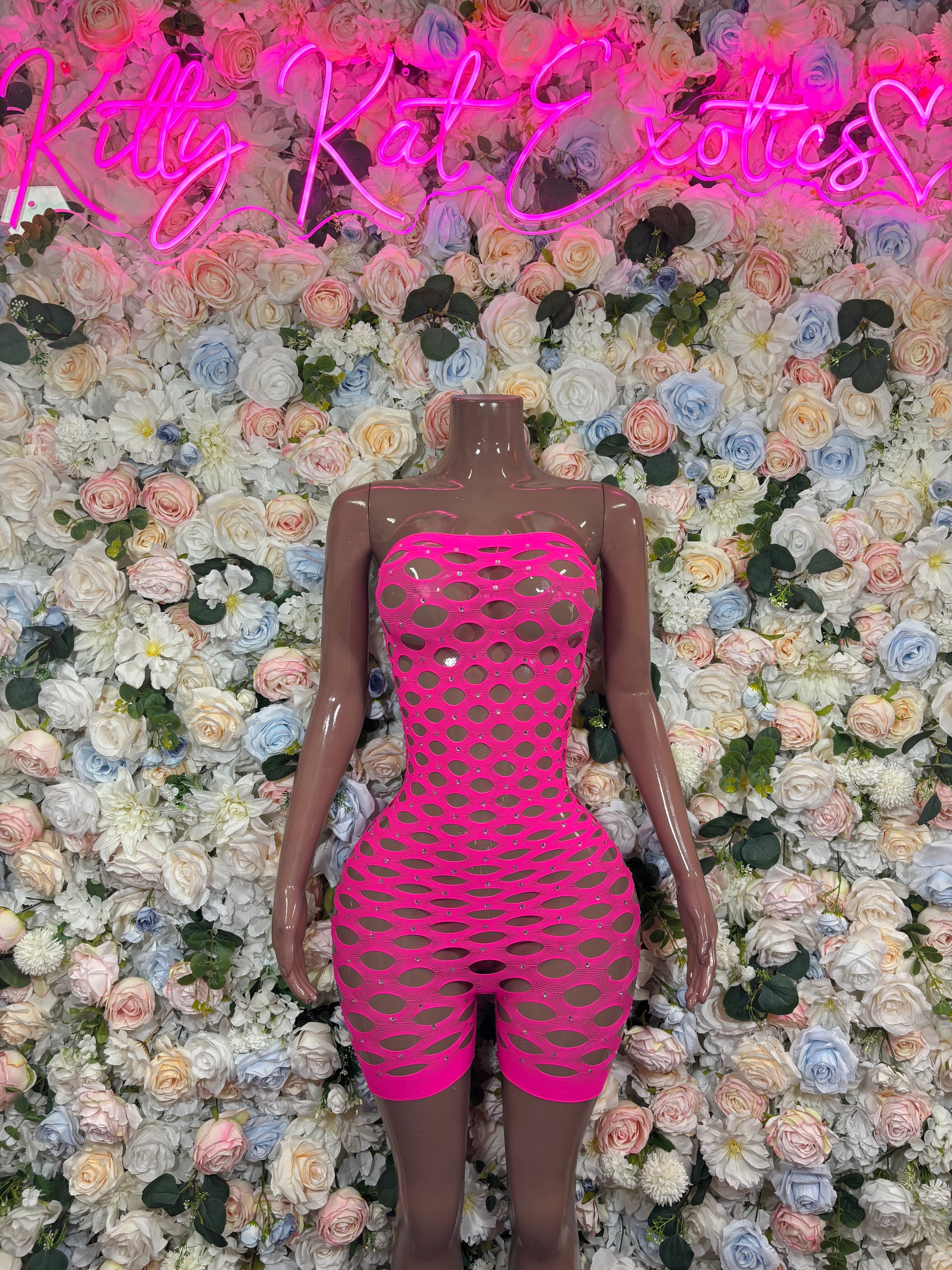 Hot pink fishnet strapless romper with allover cutout mesh and short shorts