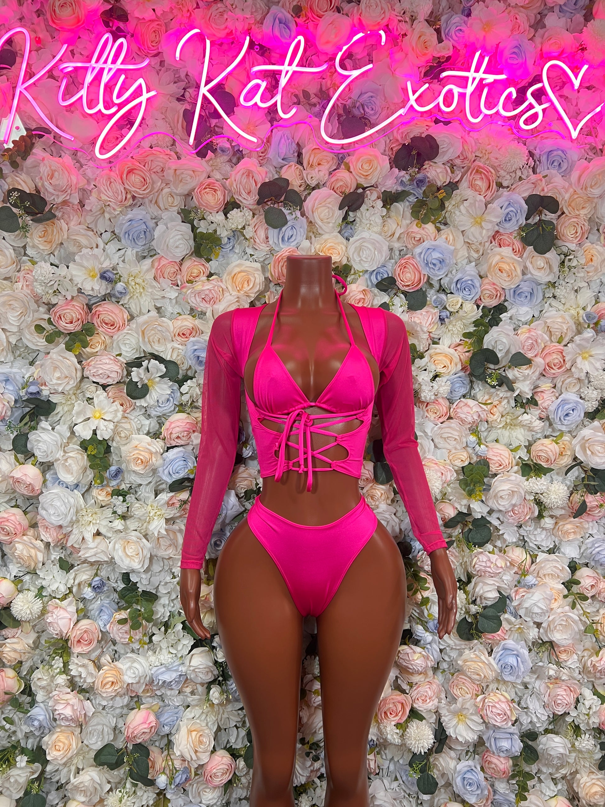 Pink bodysuit club wear displayed on mannequin against floral background, ideal for exotic dancewear and club outings.