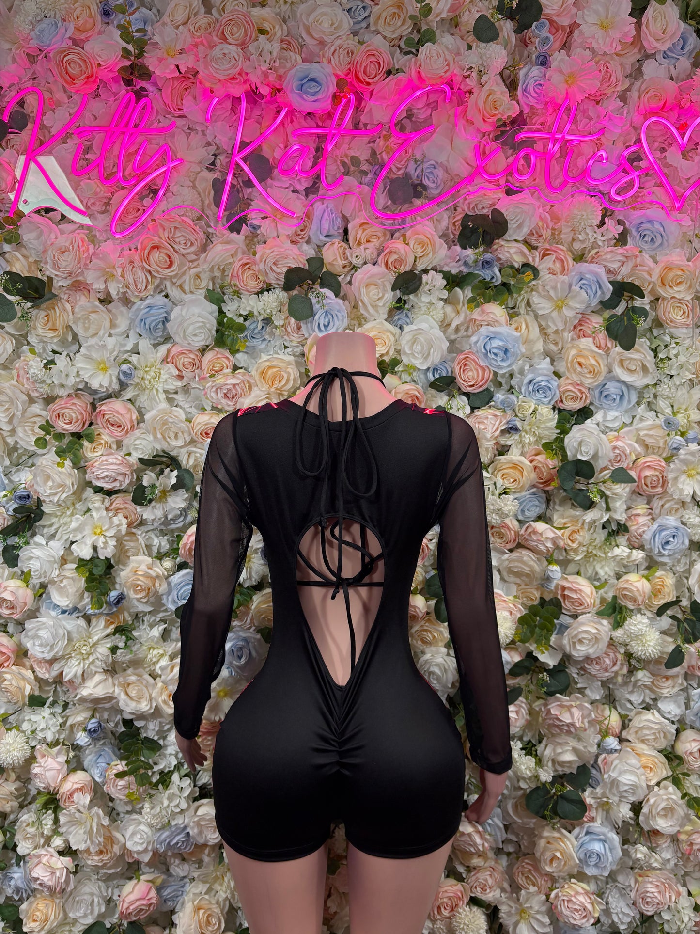 Back view of black one-piece bodysuit with red neon lines, crisscross cutout and sheer sleeves