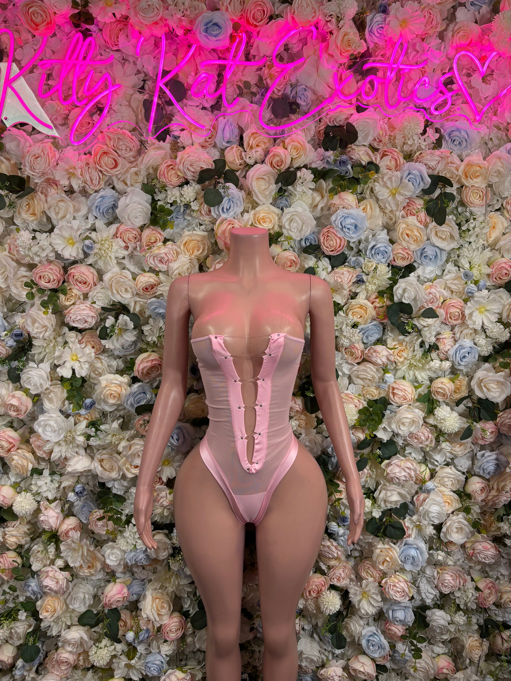 Pink one-piece bodysuit with corset-style seams and high-cut legs, thin adjustable straps