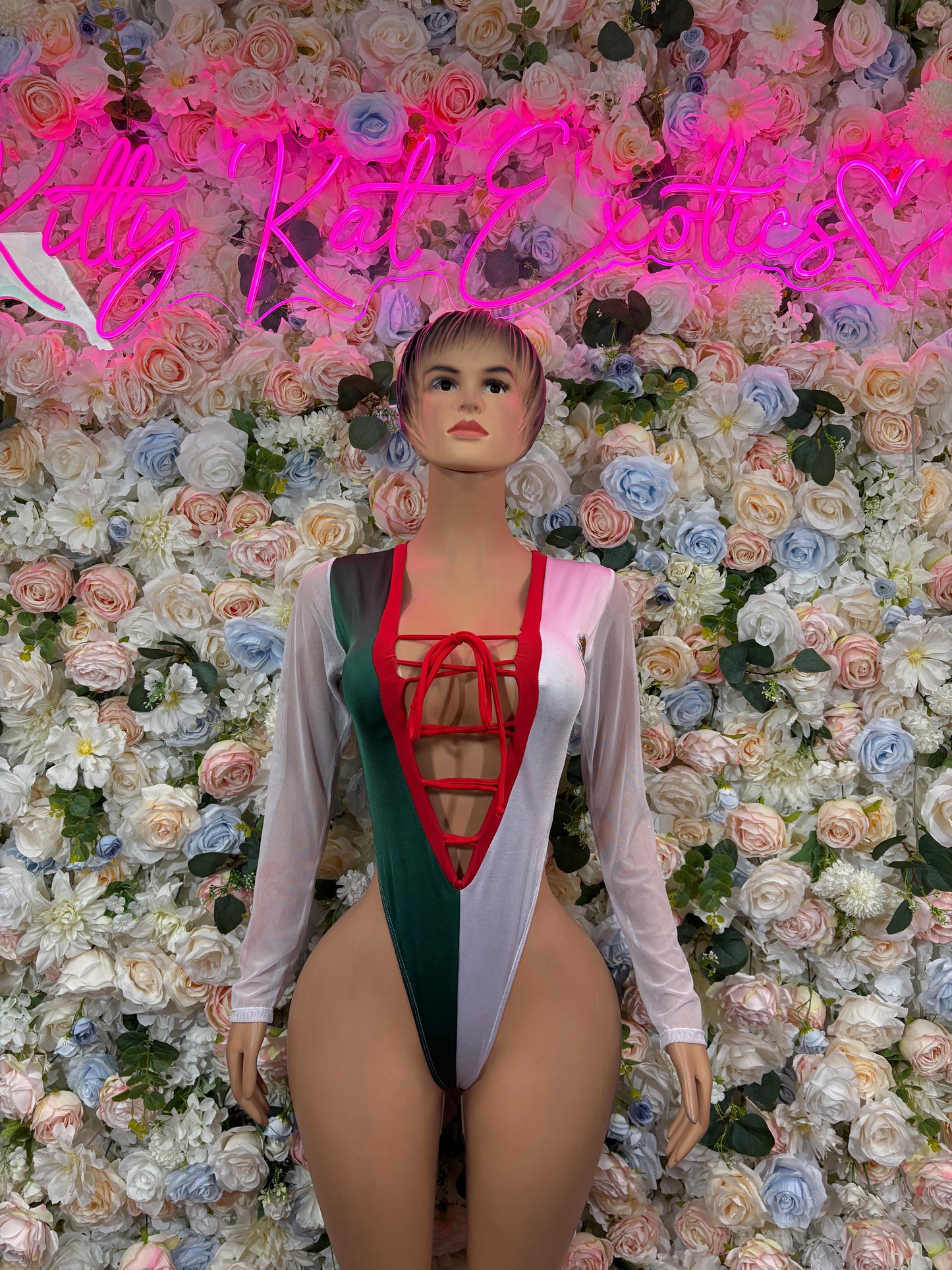 White one-piece bodysuit with long sleeves, green panel and red lace-up front