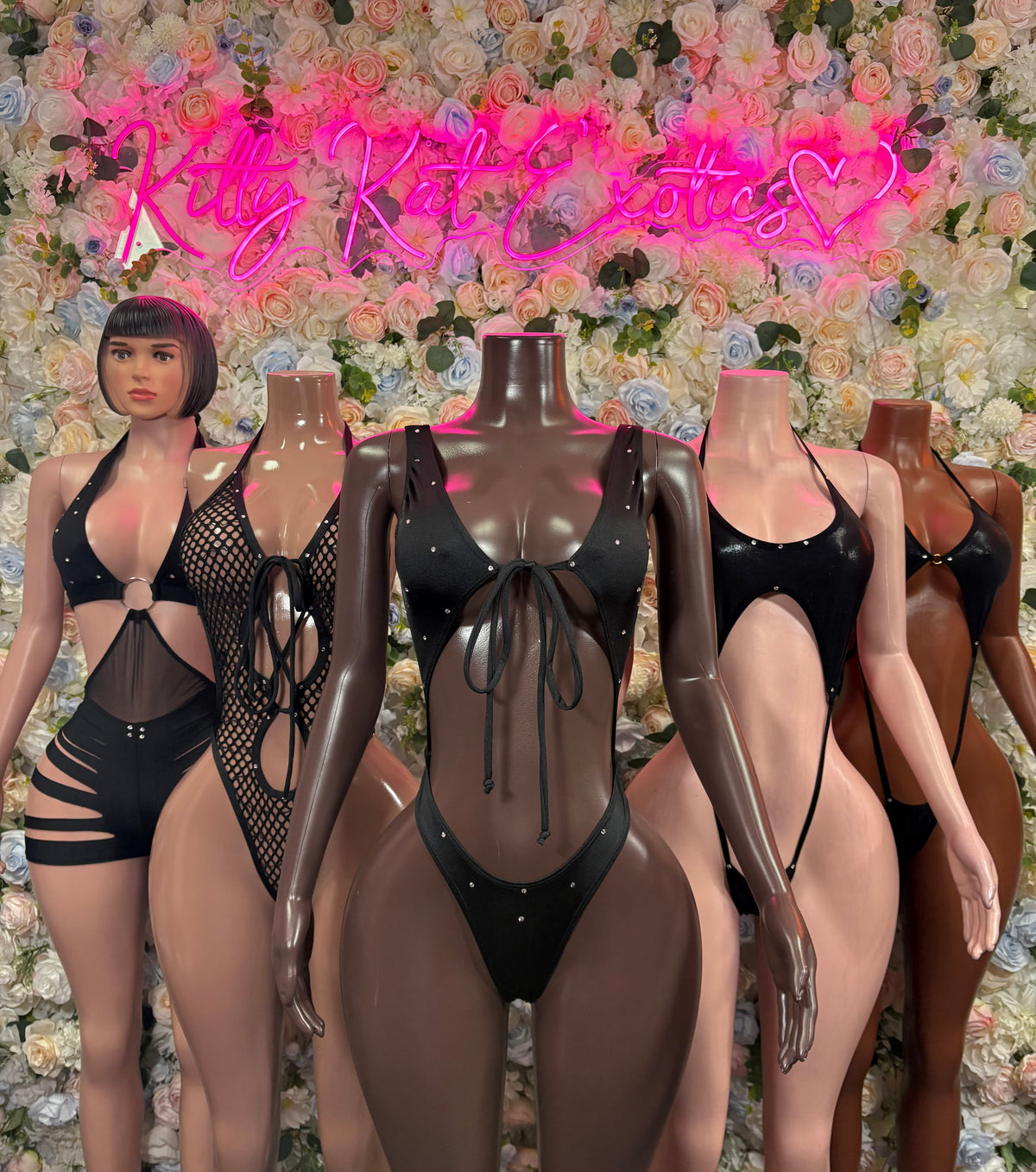 Black fishnet mesh one-piece bodysuit on mannequins, high-cut with lace-up detail