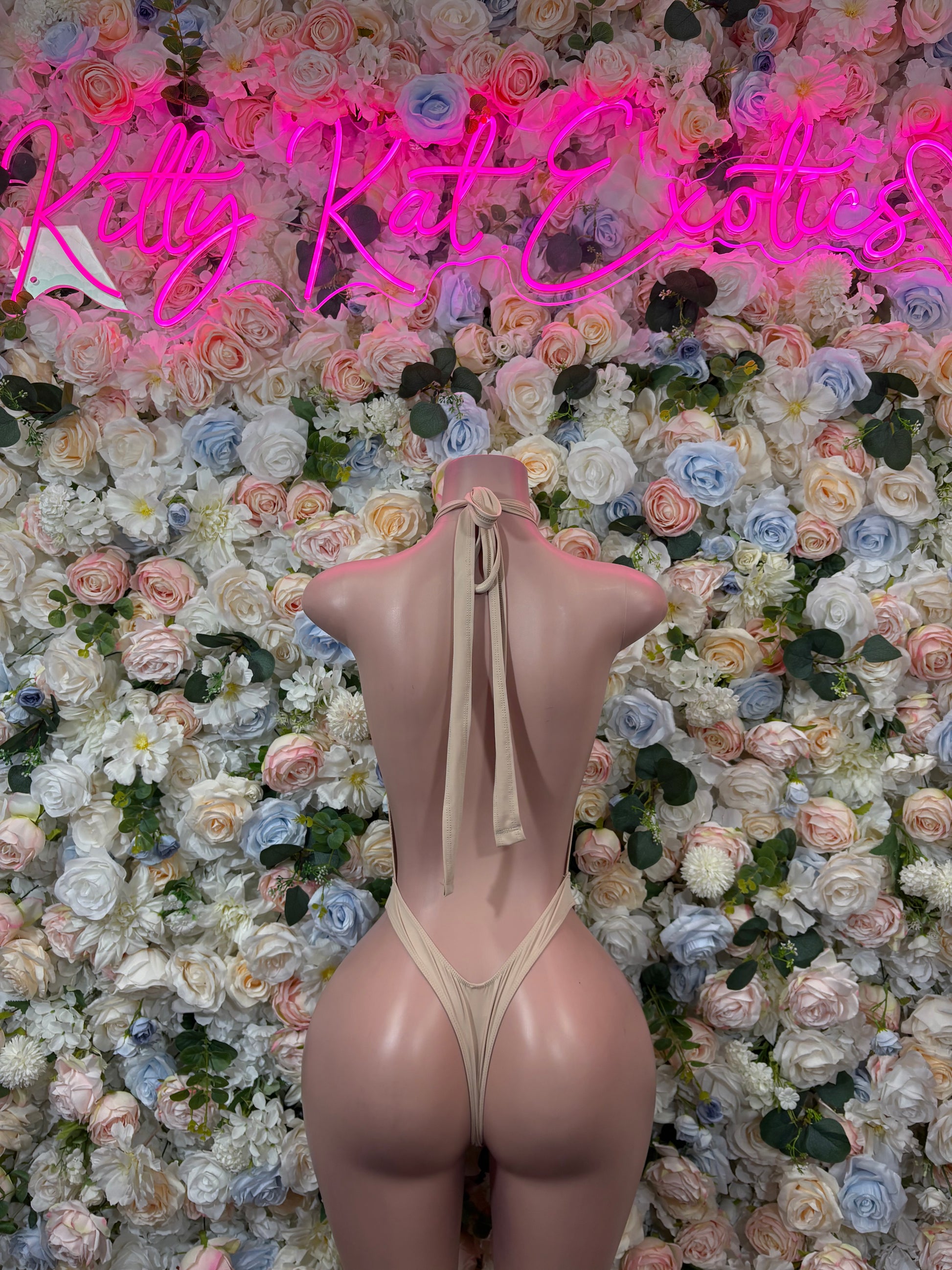 Nude backless bodysuit with crisscross straps and bow tie, gold chain