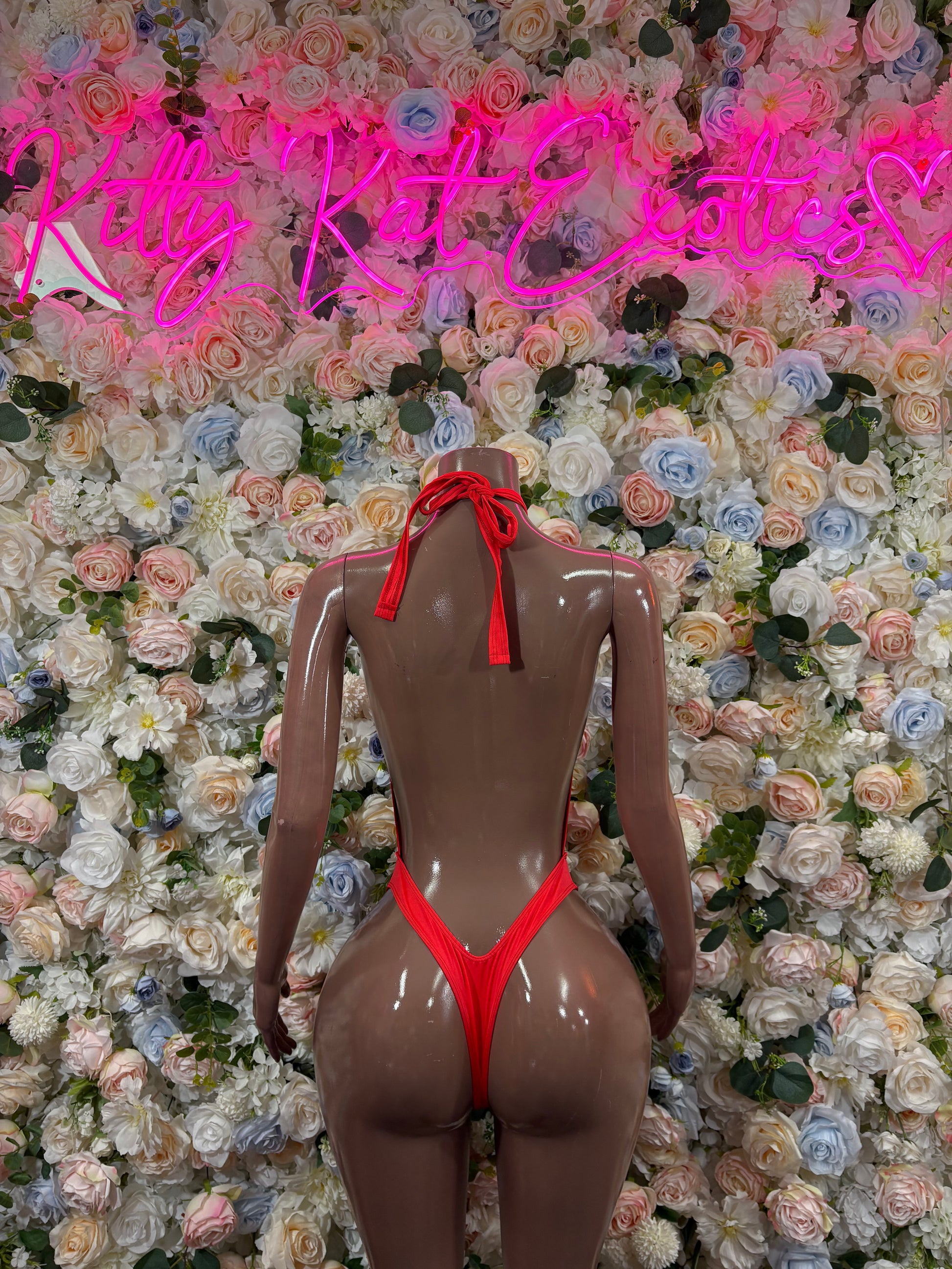 Red open-back halter bodysuit with tie at the neck and high-cut legs