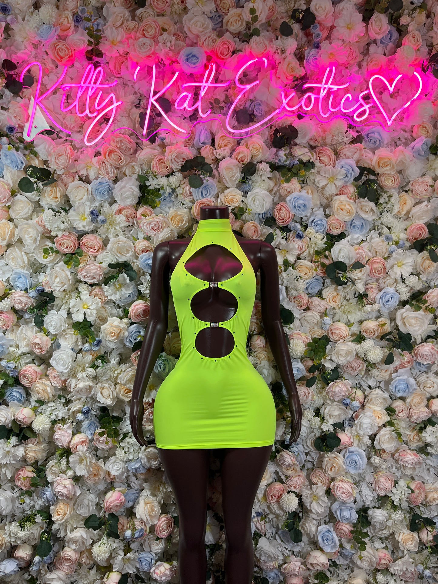 Neon green club dress with halter neckline and ruched bodice on mannequin