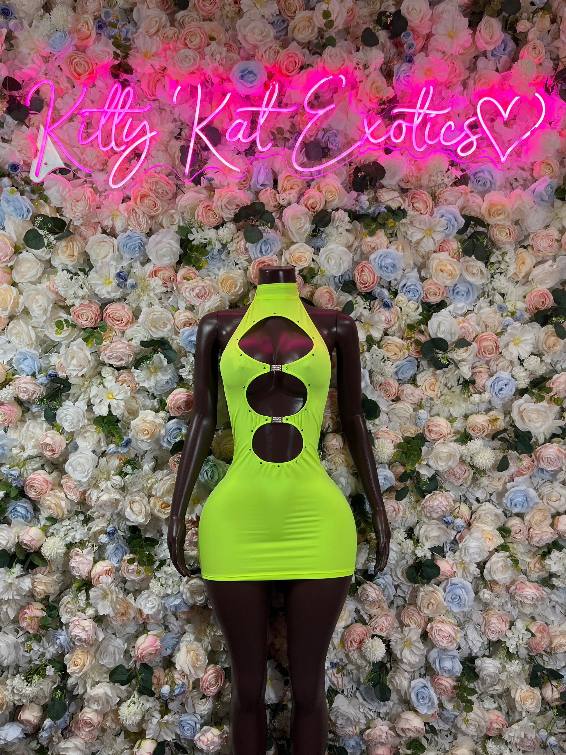 Neon green club dress with halter neckline and ruched bodice on mannequin