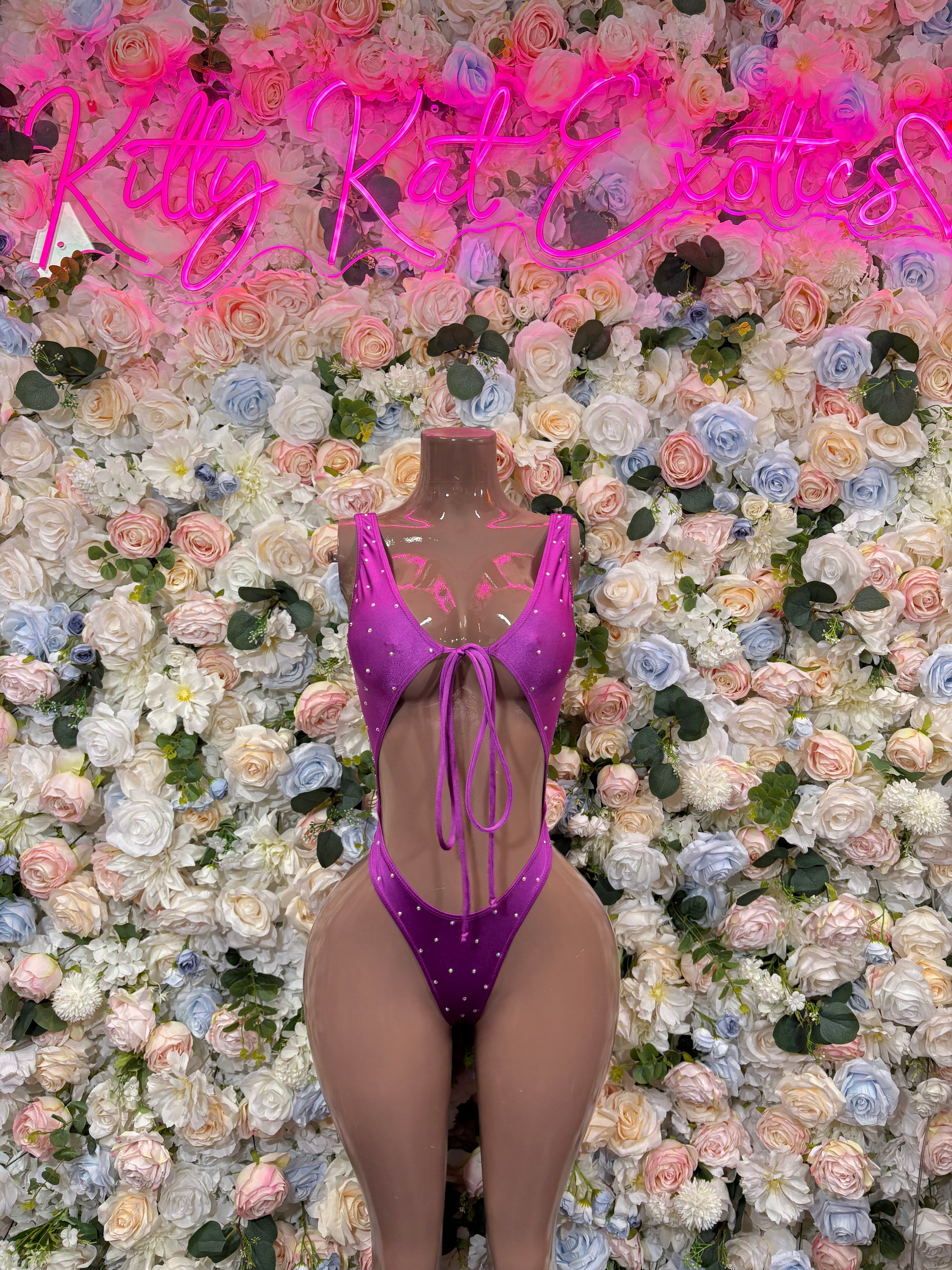 Purple one-piece rave bodysuit with halter neckline, decorative sparkle, and tie back