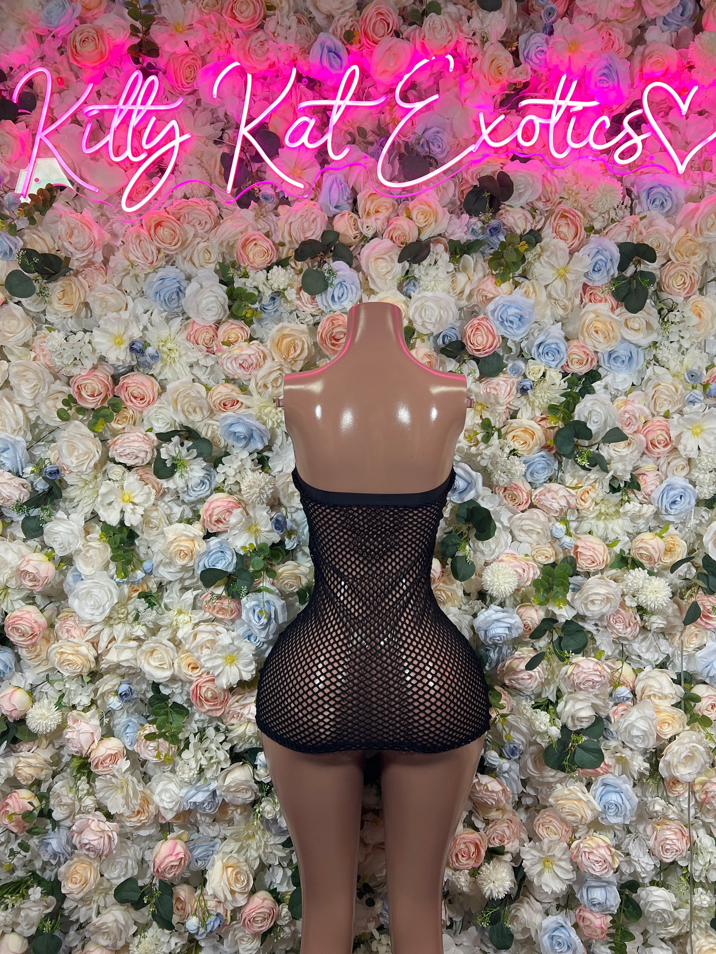 Black fishnet mini dress on mannequin, sleeveless sweetheart neckline, short hem