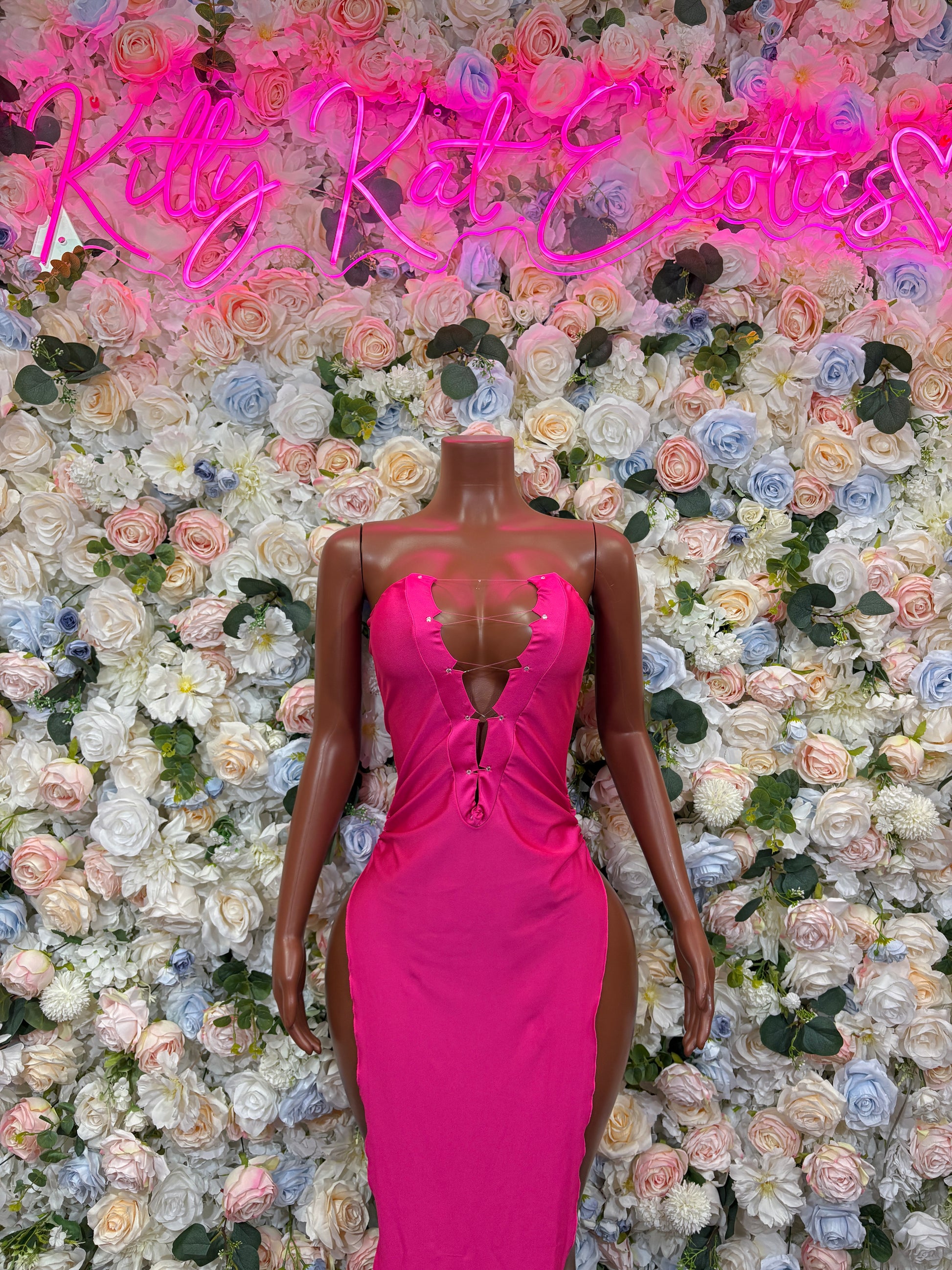 Magenta fitted gown with V-neck, ruched bodice, and front slit on mannequin