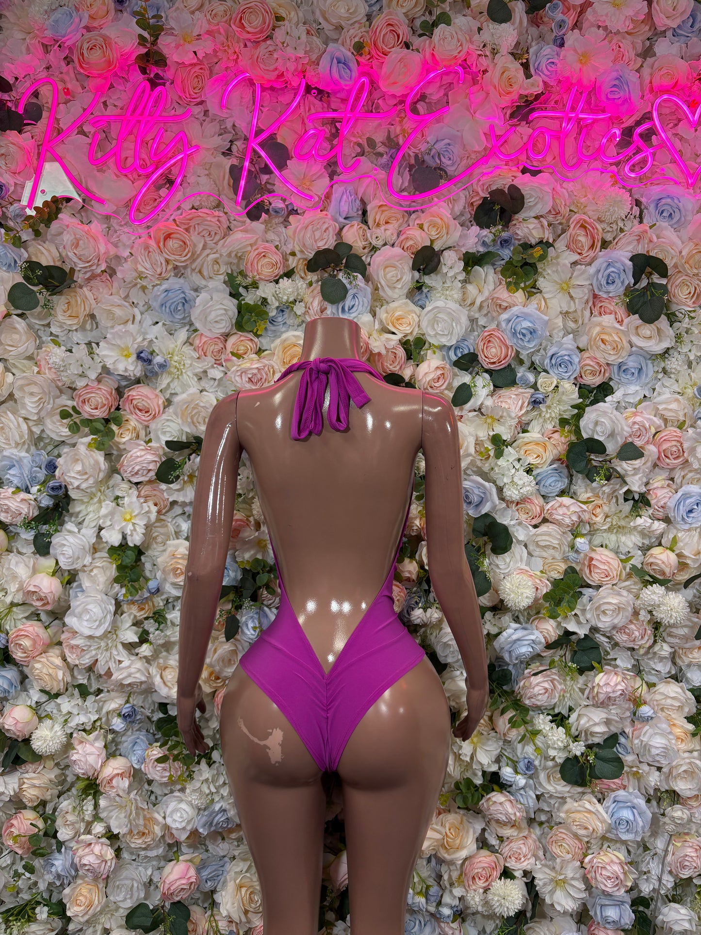 Purple one-piece rave bodysuit with open back, tie straps, and V-shaped back dip
