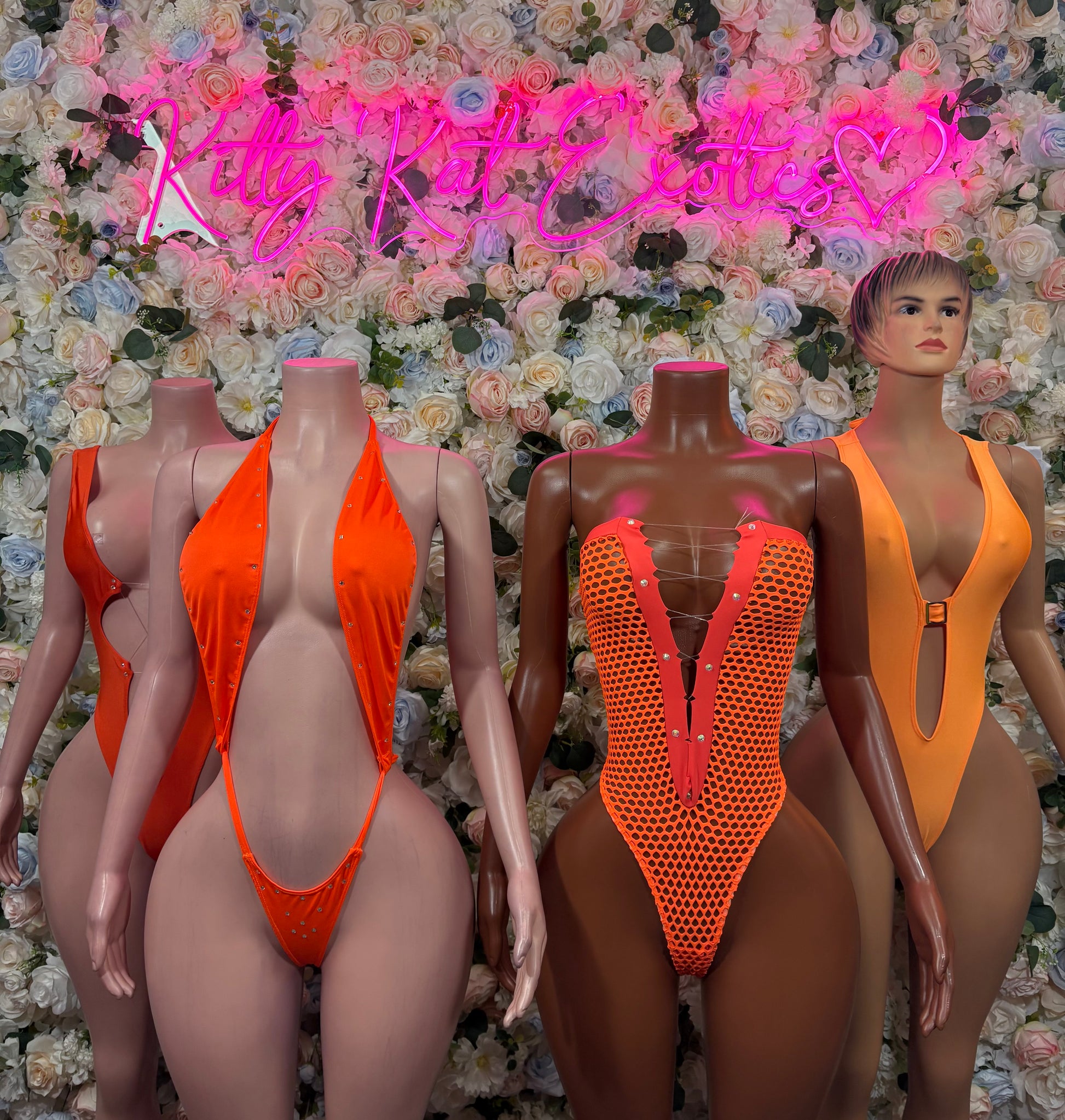 Orange bodysuit display on mannequins: solid V-neck front and red mesh panel bodysuit