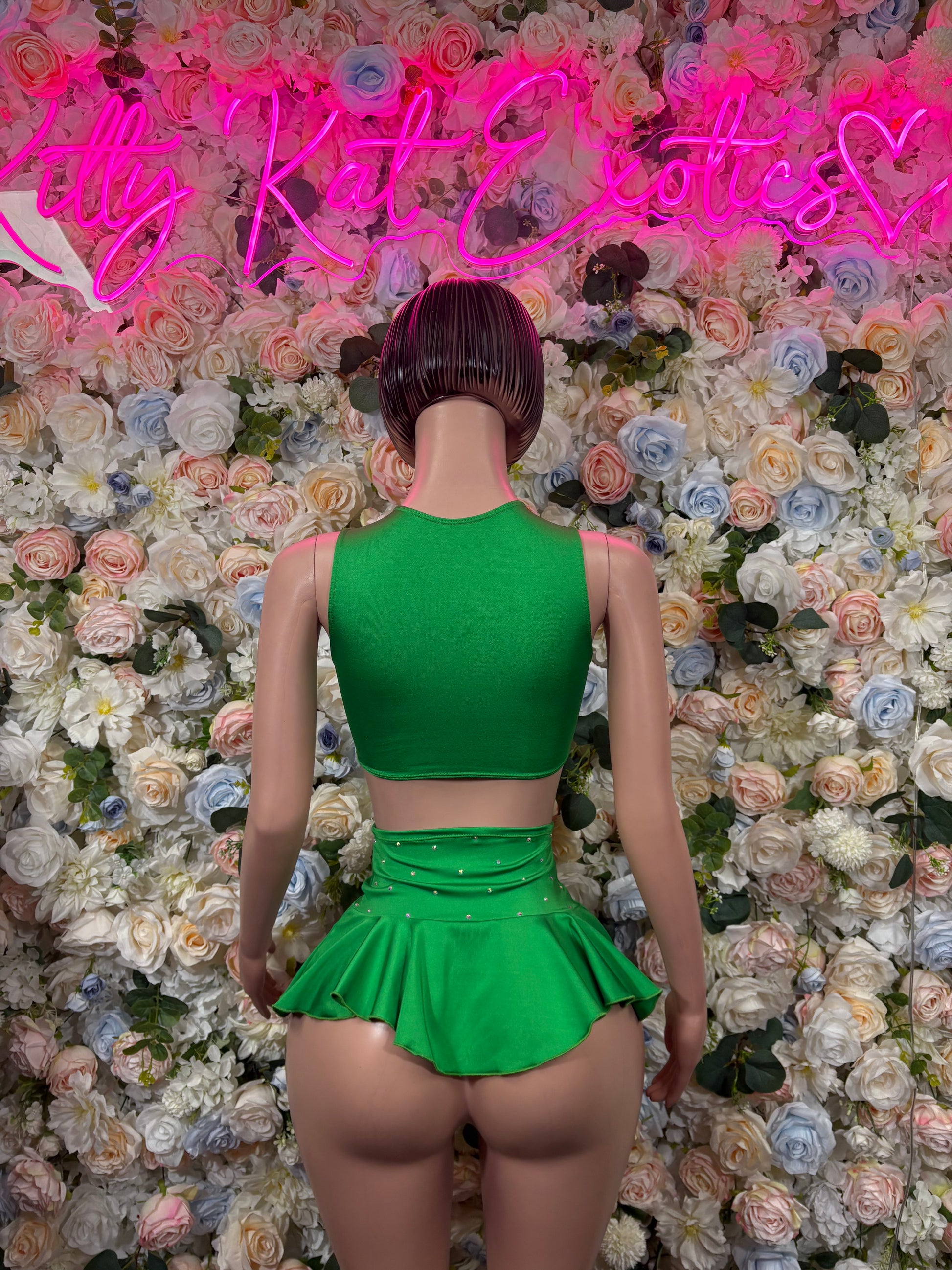 Green two-piece skirt set with racer-back crop top and flared mini skirt, back view