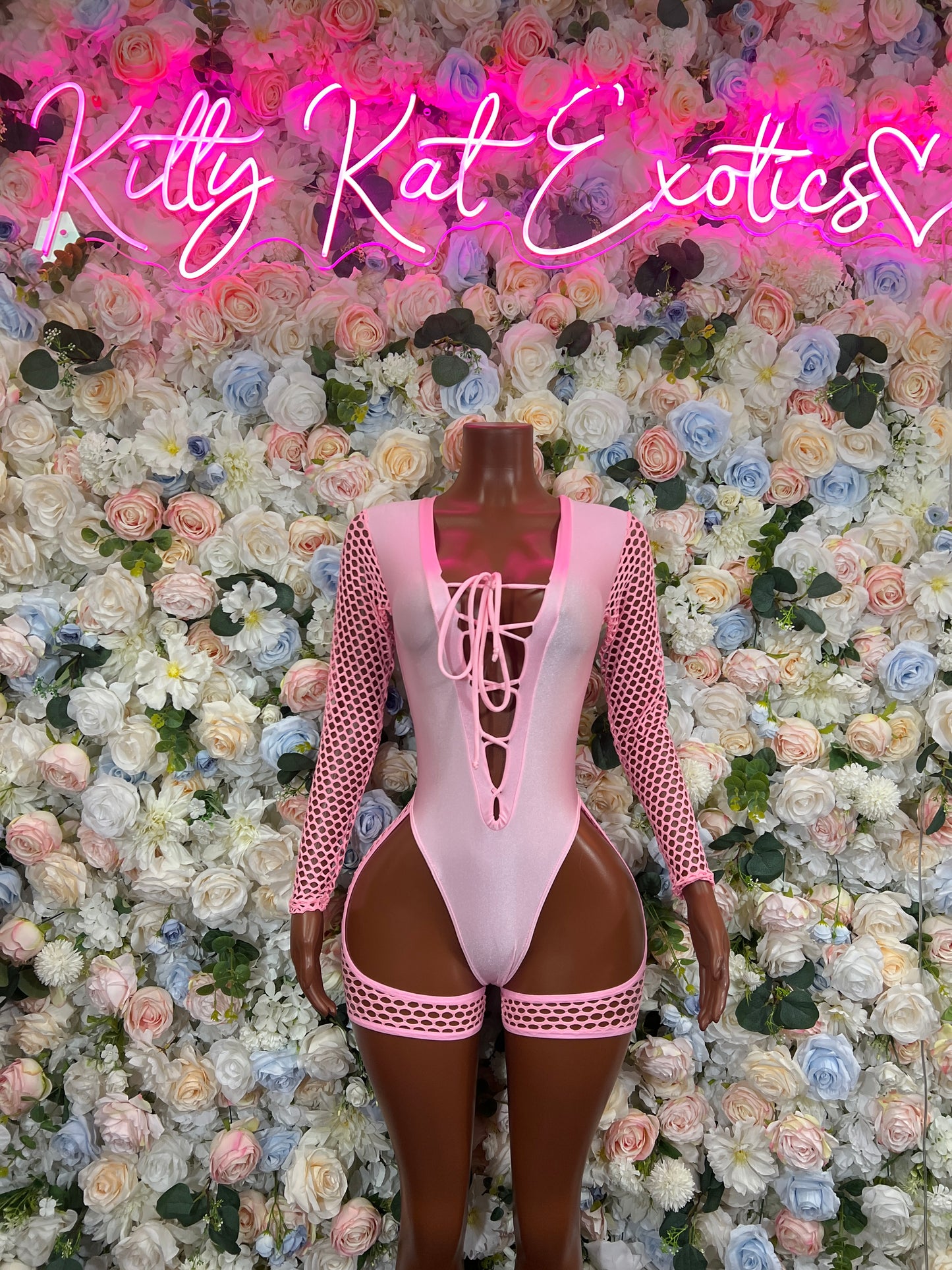 Pink bodysuit with fishnet sleeves, lace-up front and high-cut leg openings with trim