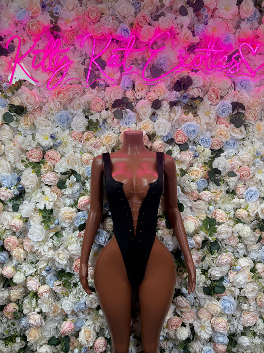 Black one-piece bodysuit with deep V neckline and thin straps on mannequin