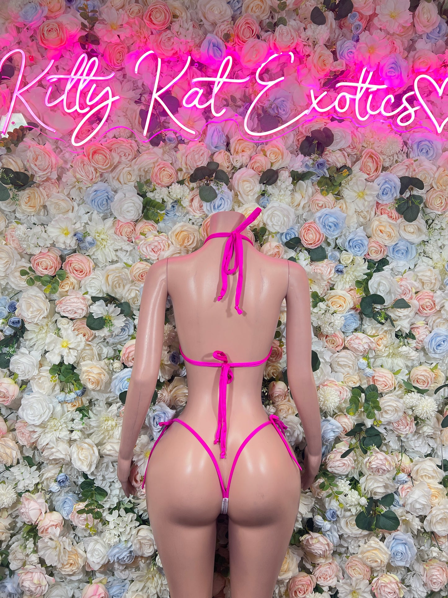 Pink triangle string bikini with crisscross back ties on a mannequin