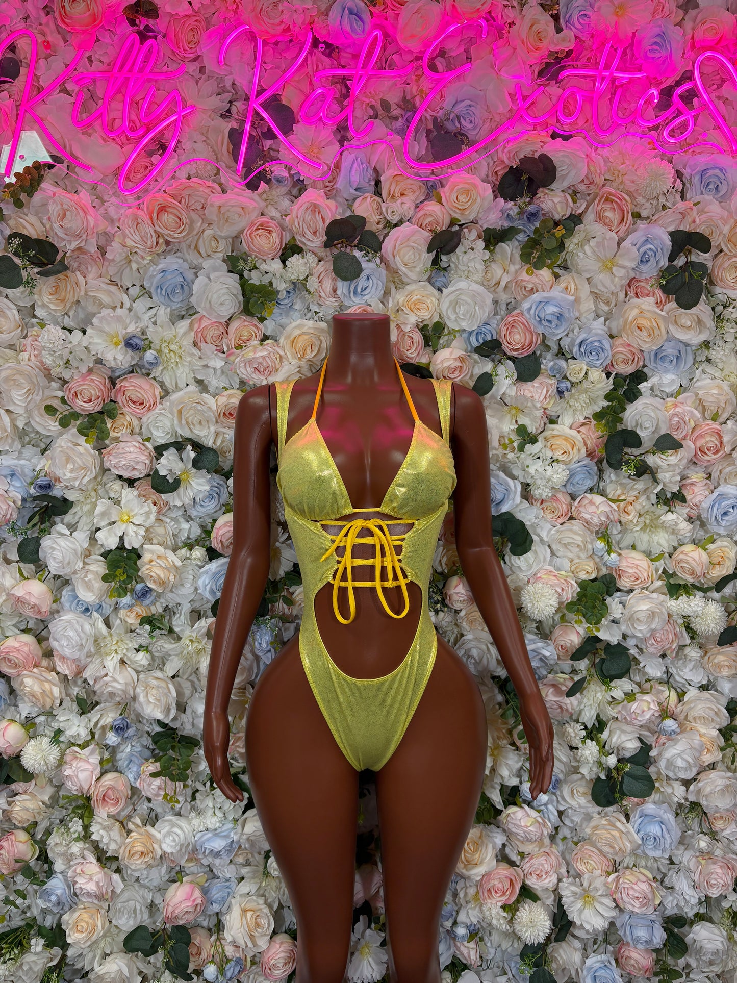 Yellow metallic one-piece bodysuit with crisscross front straps and tie neck.