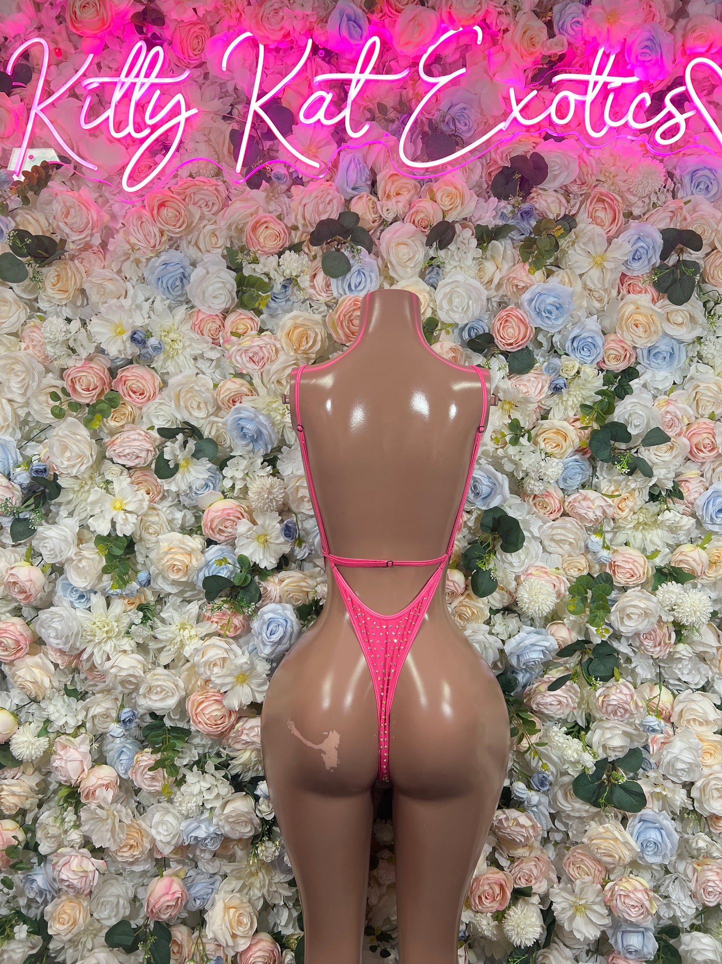 Pink rhinestone V-neck bodysuit on mannequin, thin straps and high-cut sides