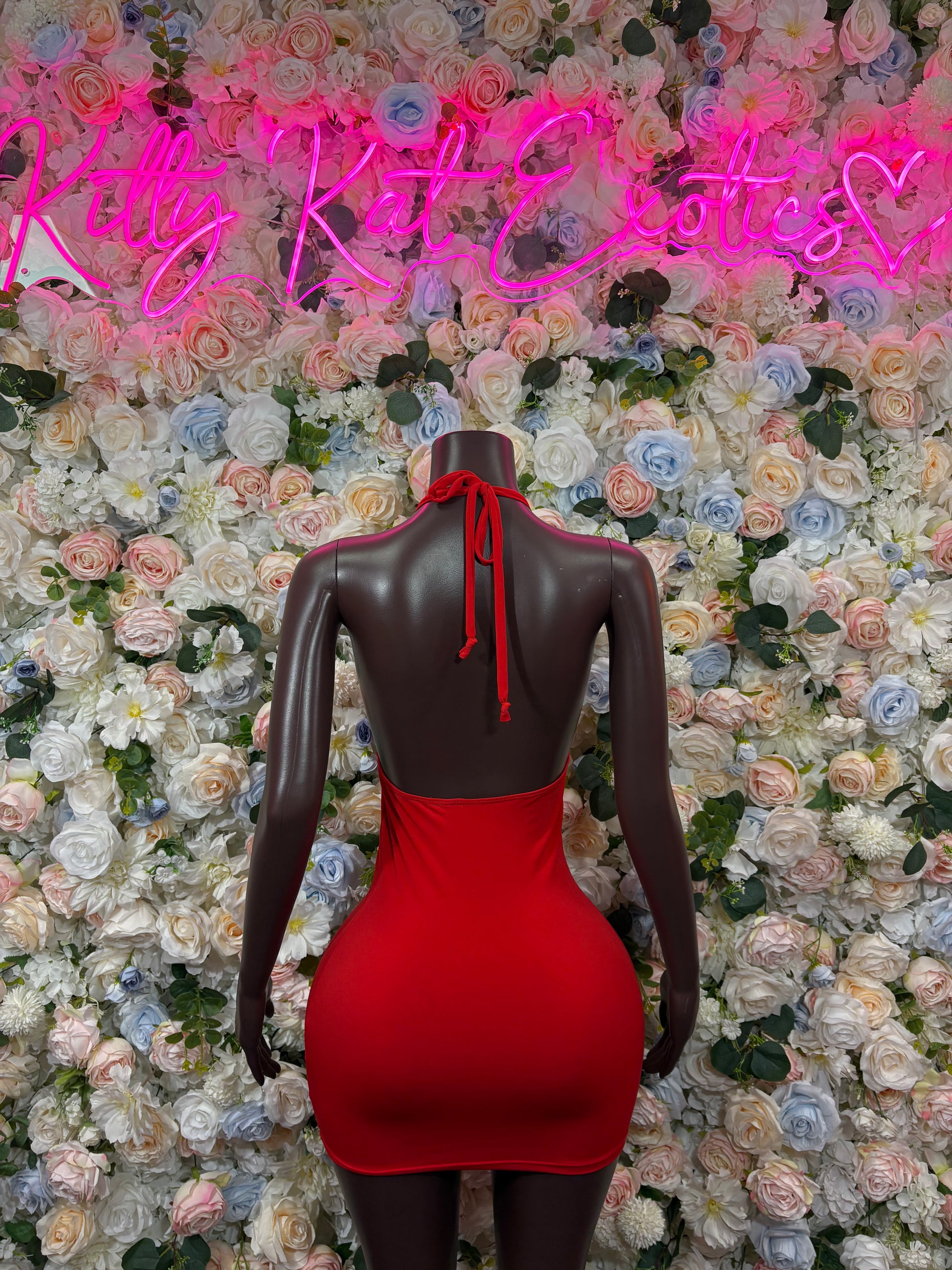Red open-back mini dress on mannequin, halter straps tied at upper back