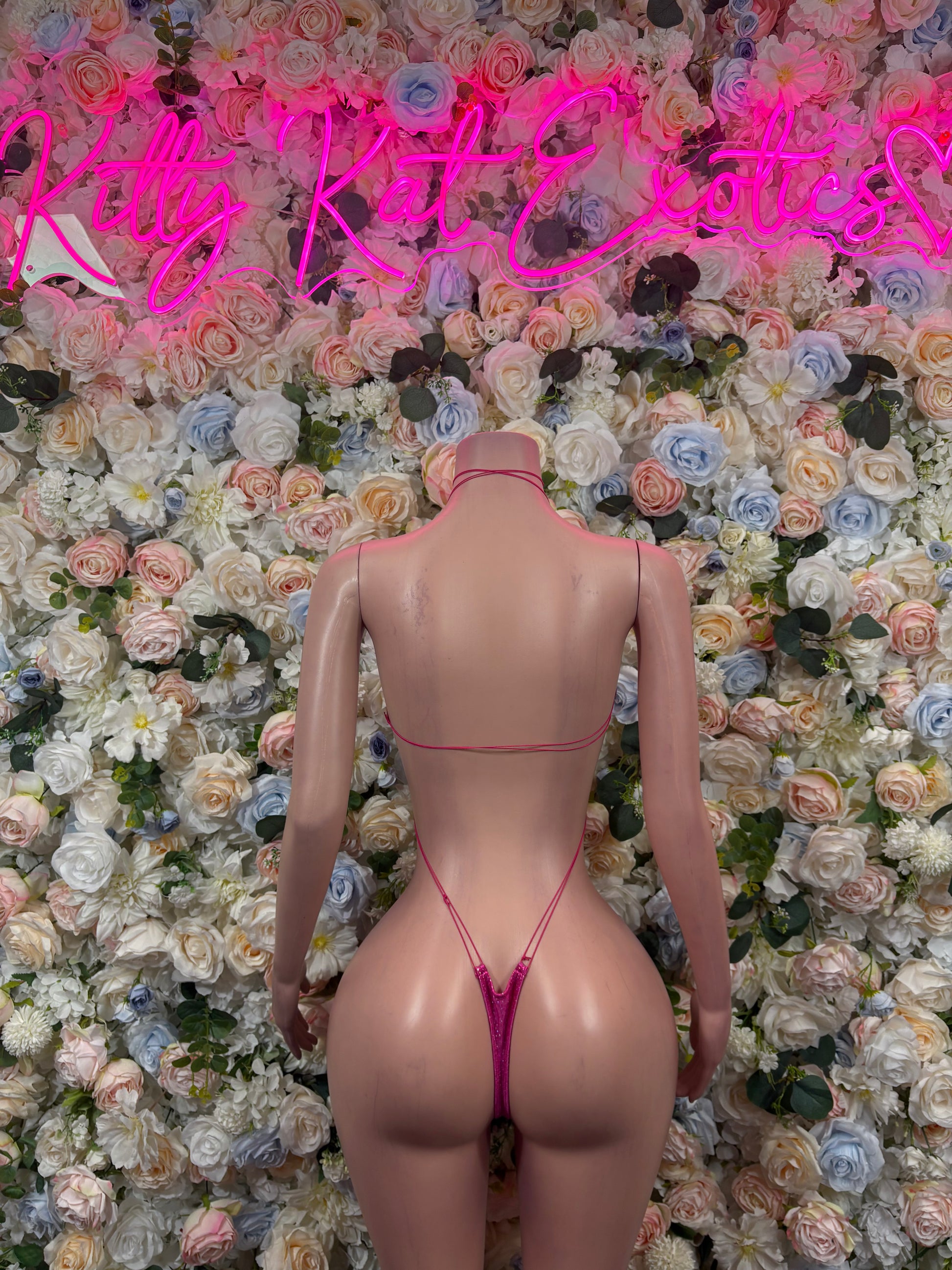 Back view of pink metallic halter bodysuit with thong strap and high-cut legs