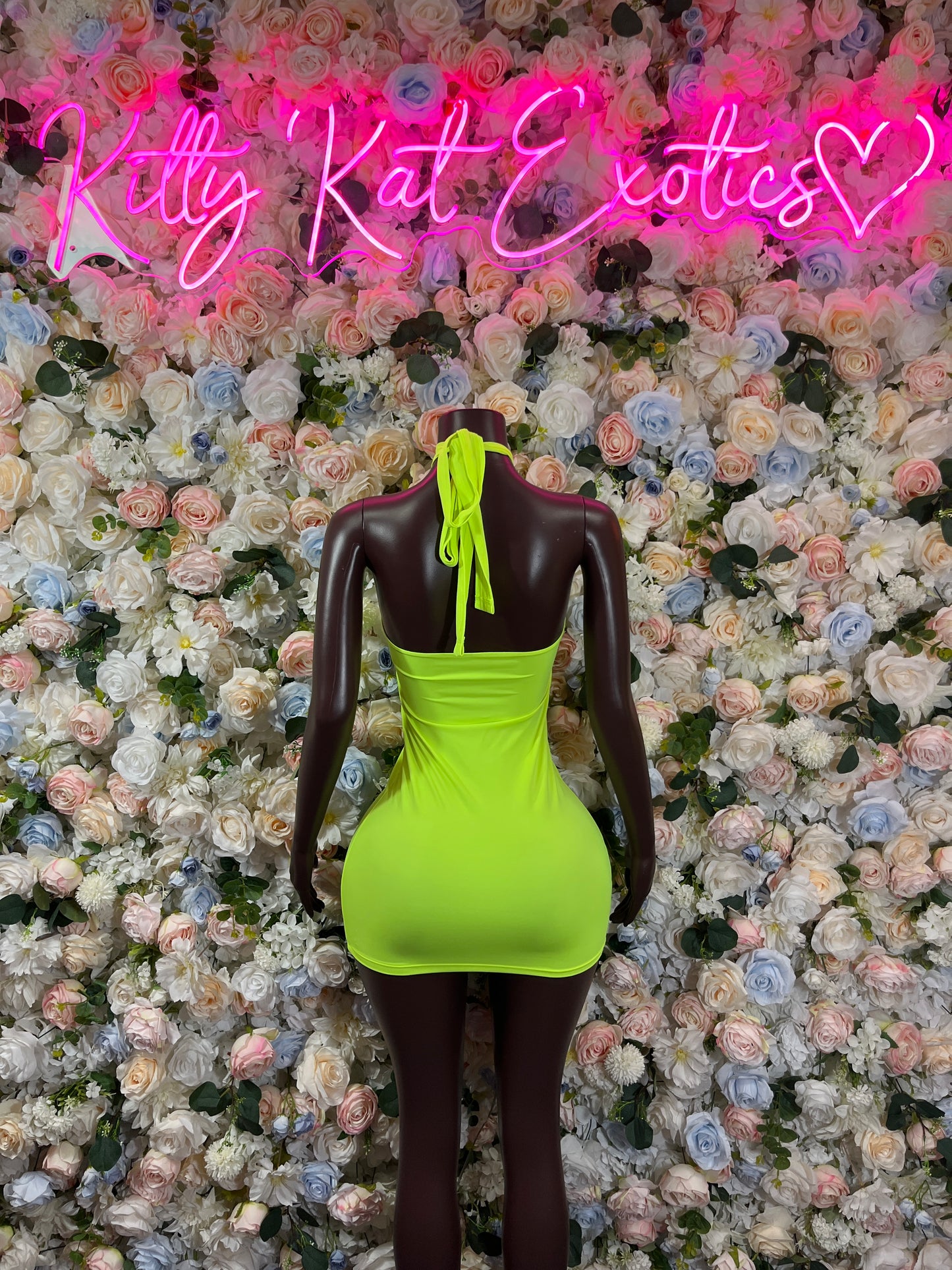 Neon green mini dress with halter straps and open back on mannequin
