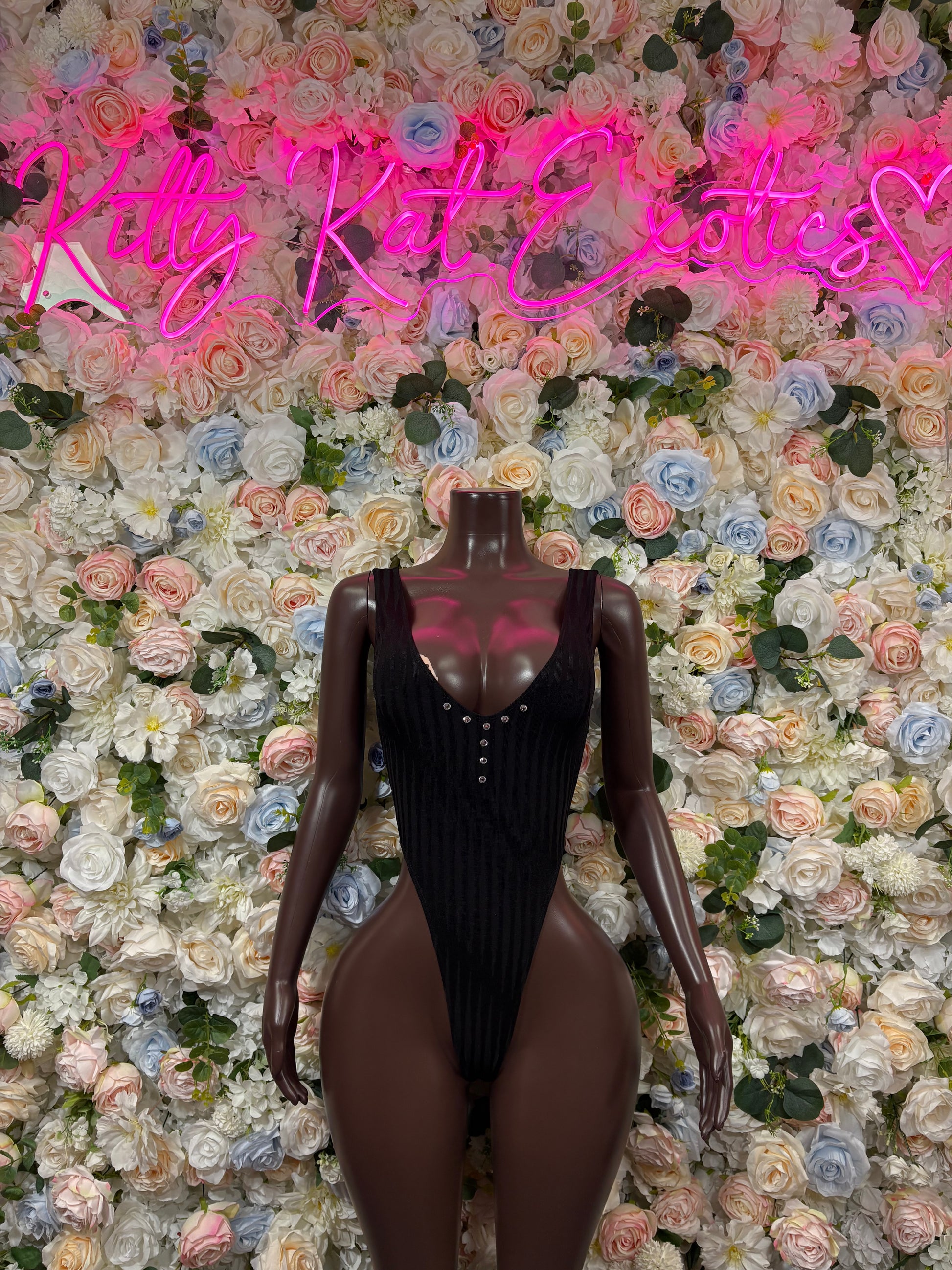 Black one-piece bodysuit with plunging neckline and long sleeves, stud accents.