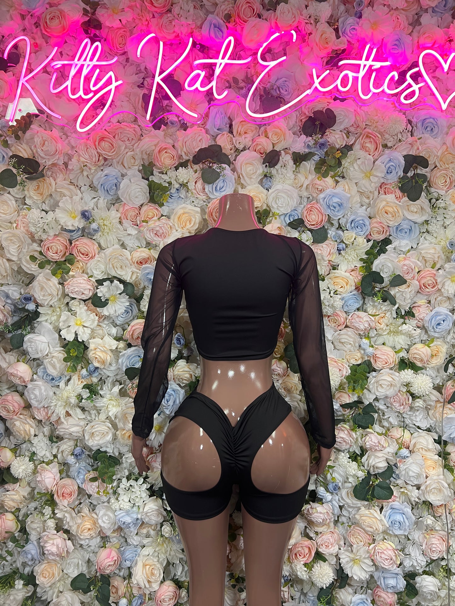Black lace-up bodysuit with sheer long sleeves and low back; short bottoms