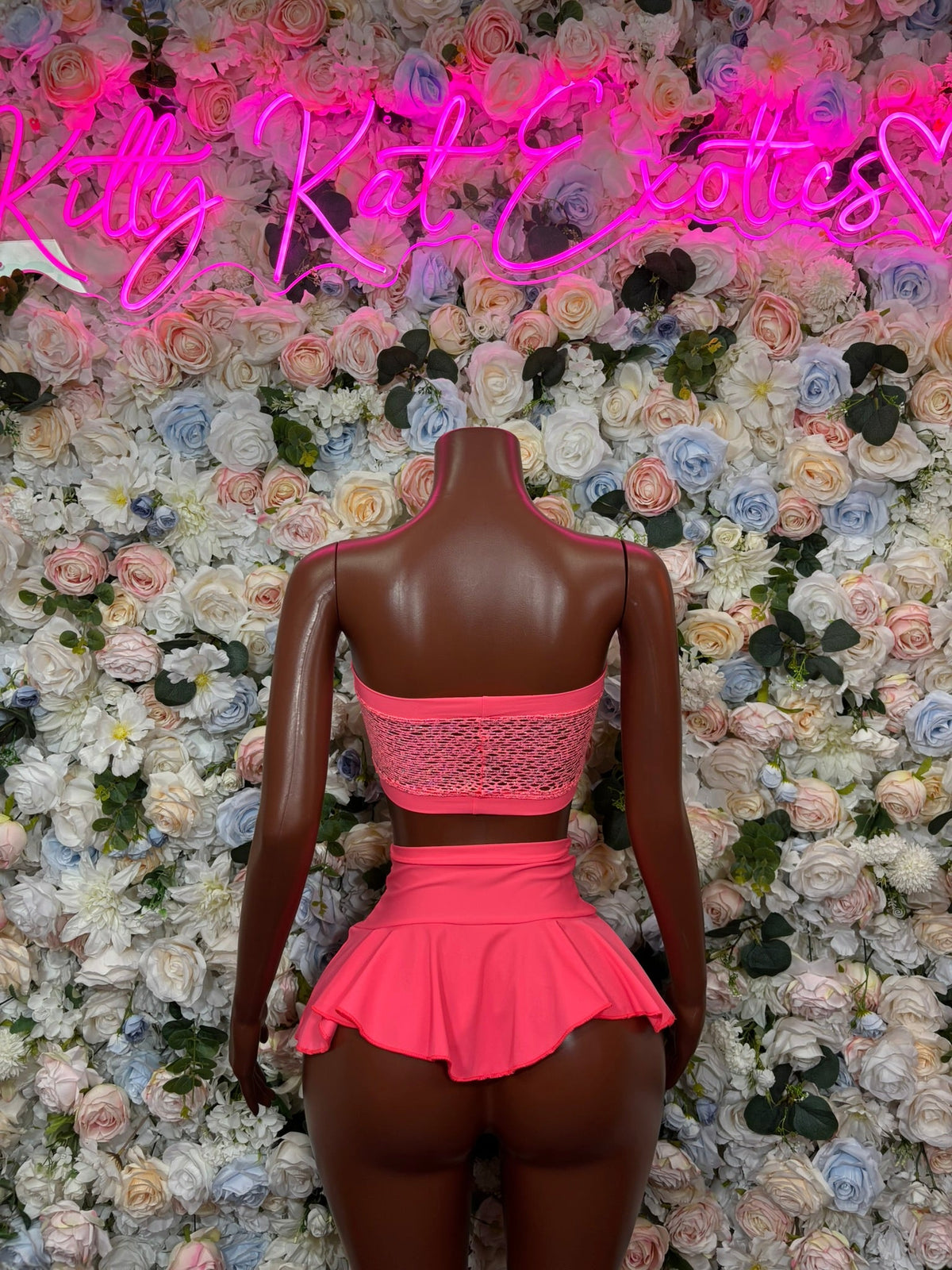 Coral pink bandeau mini skirt set, back view: textured bandeau top, ruffled mini skirt