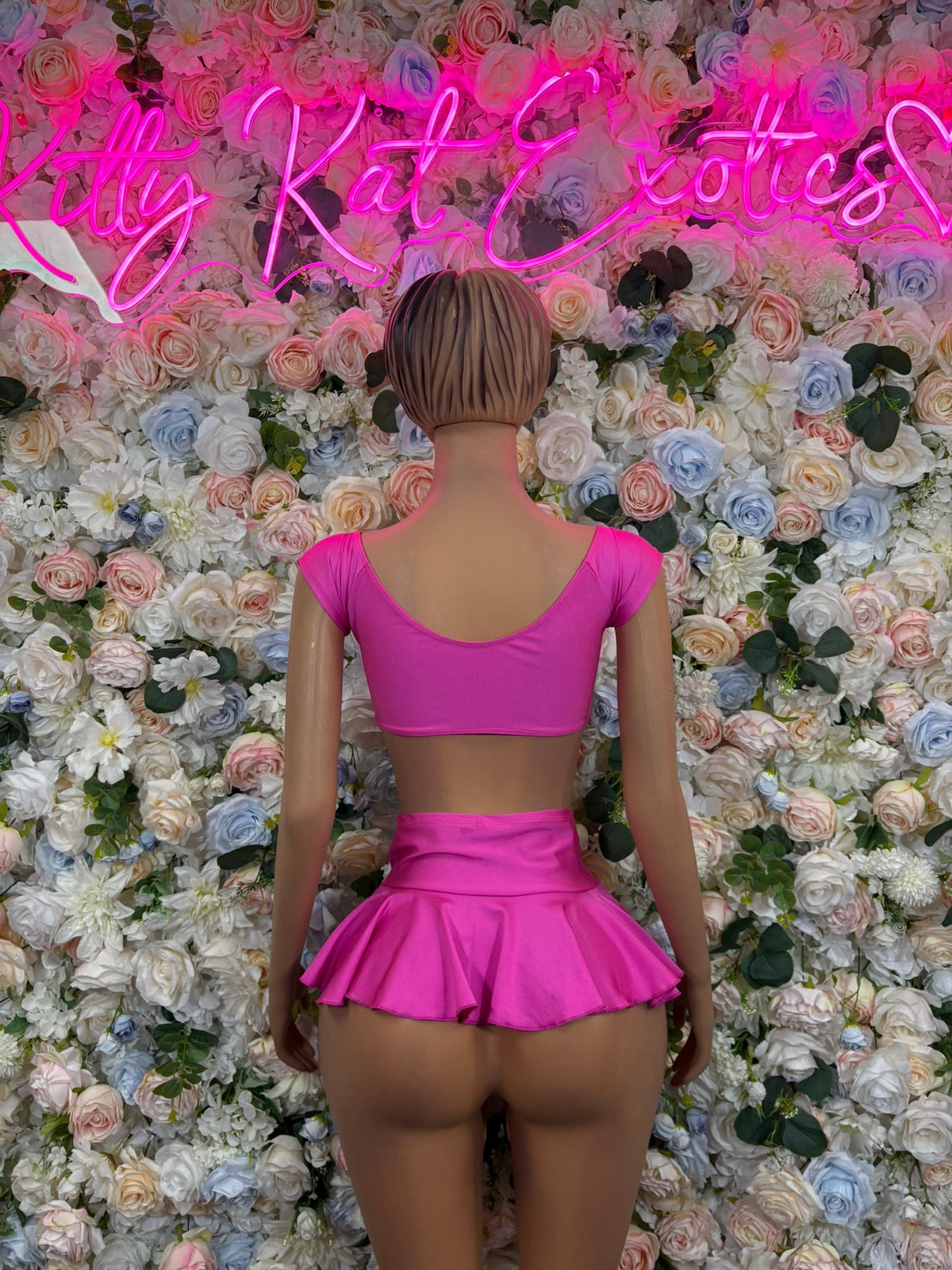 Fuchsia pink open-back crop top with matching flared mini skirt on mannequin