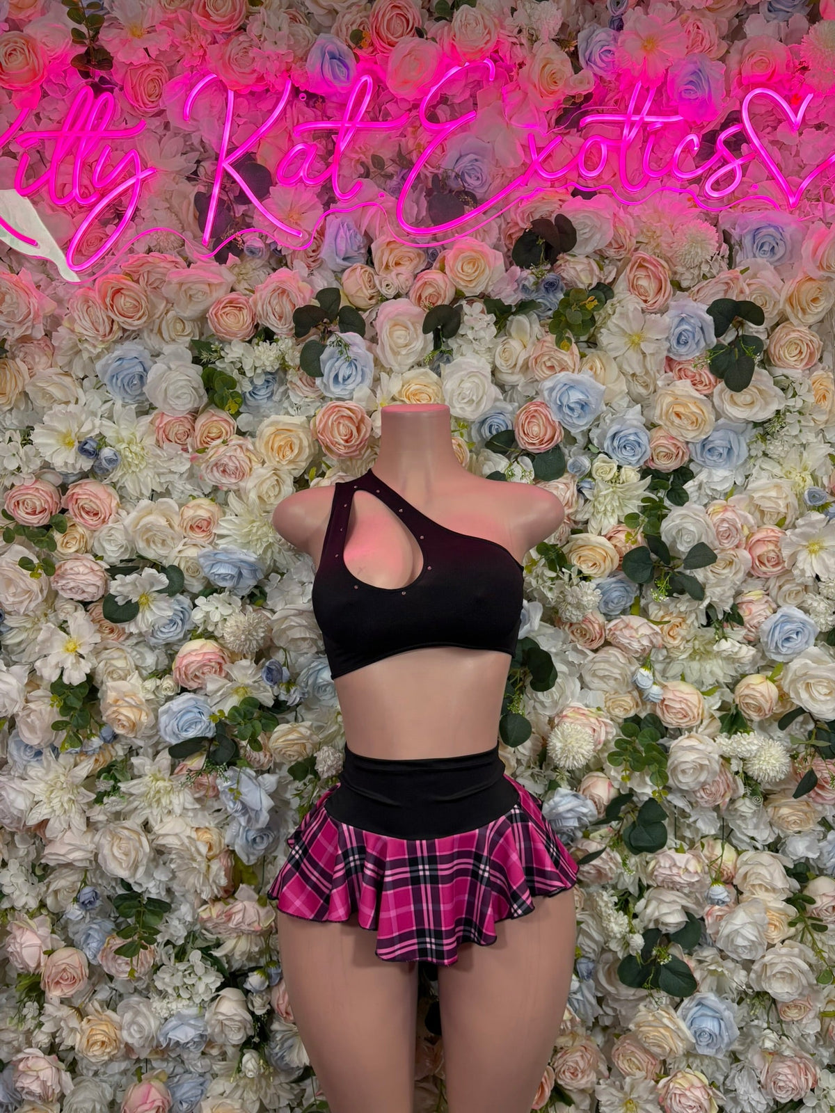 Black open-back crop top and pink plaid ruffle mini skirt set on mannequin